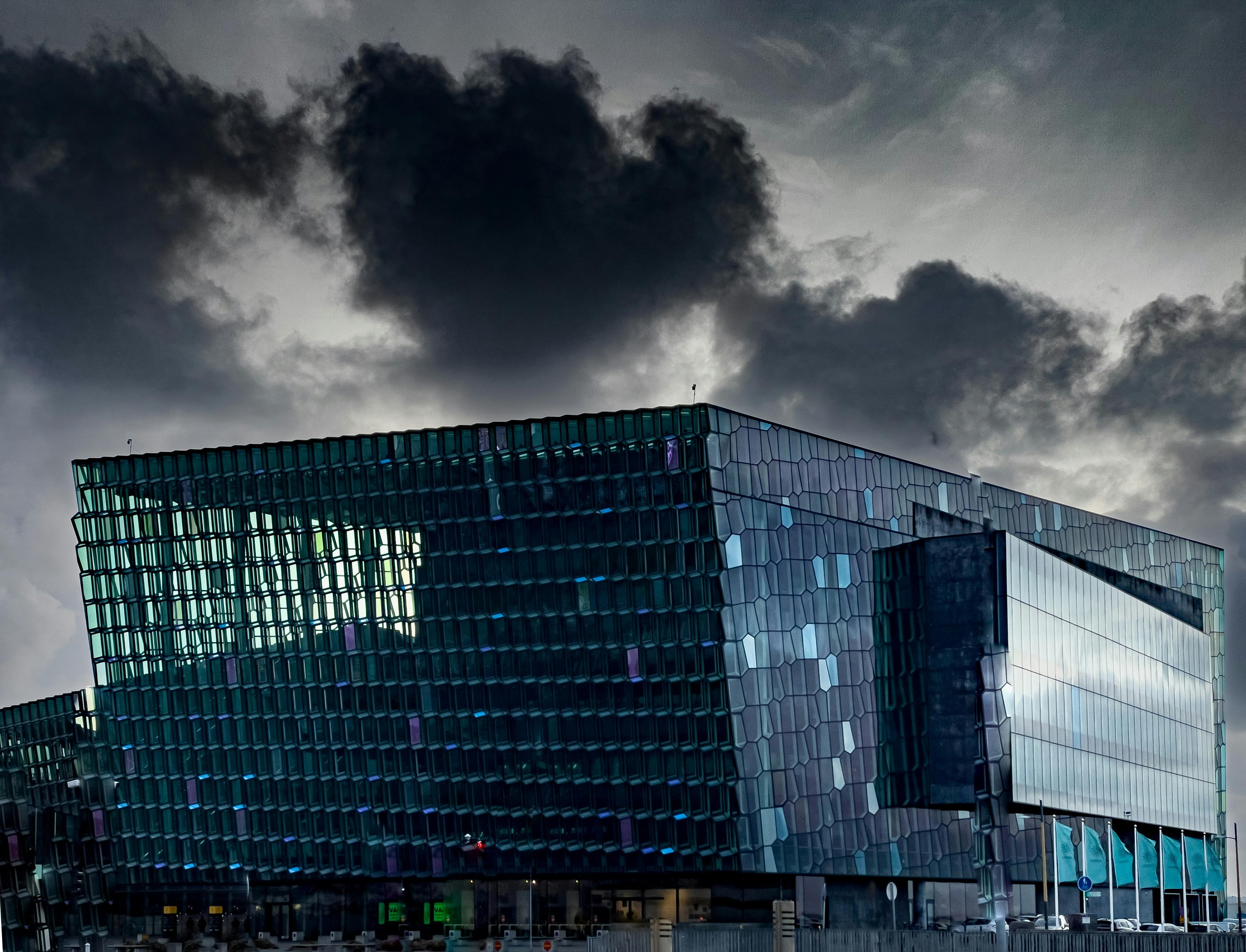 Harpa Concert Hall's modern glass facade in Reykjavík against a dramatic cloudy sky.