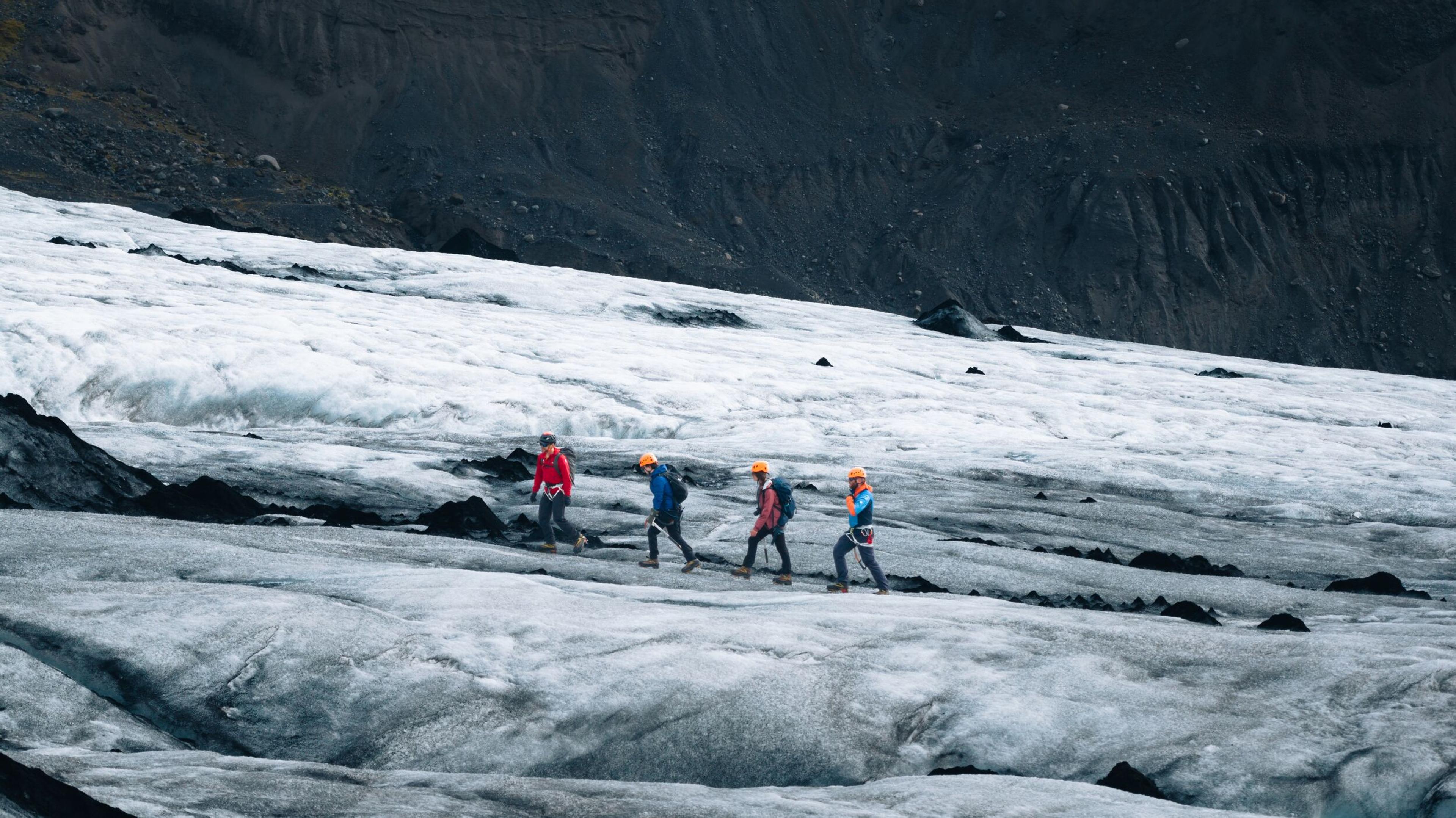 a group of people are walking on a glacier .
