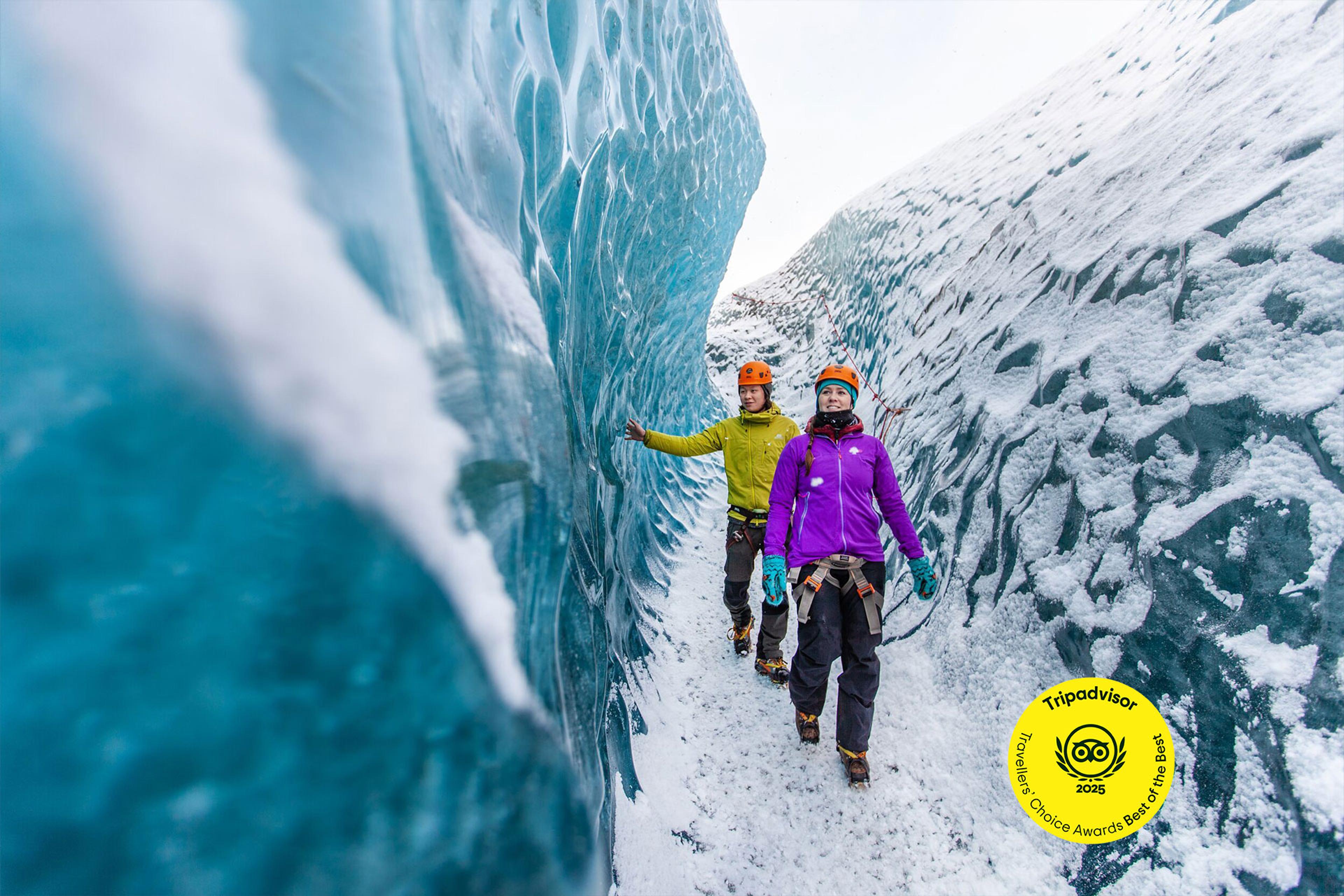 a couple of people are standing next to a large ice wall .