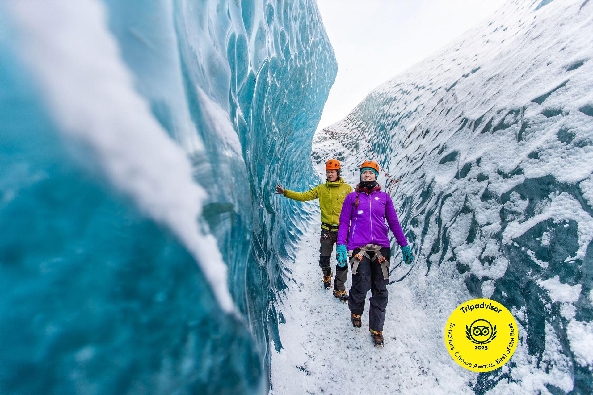 a couple of people are standing next to a large ice wall .
