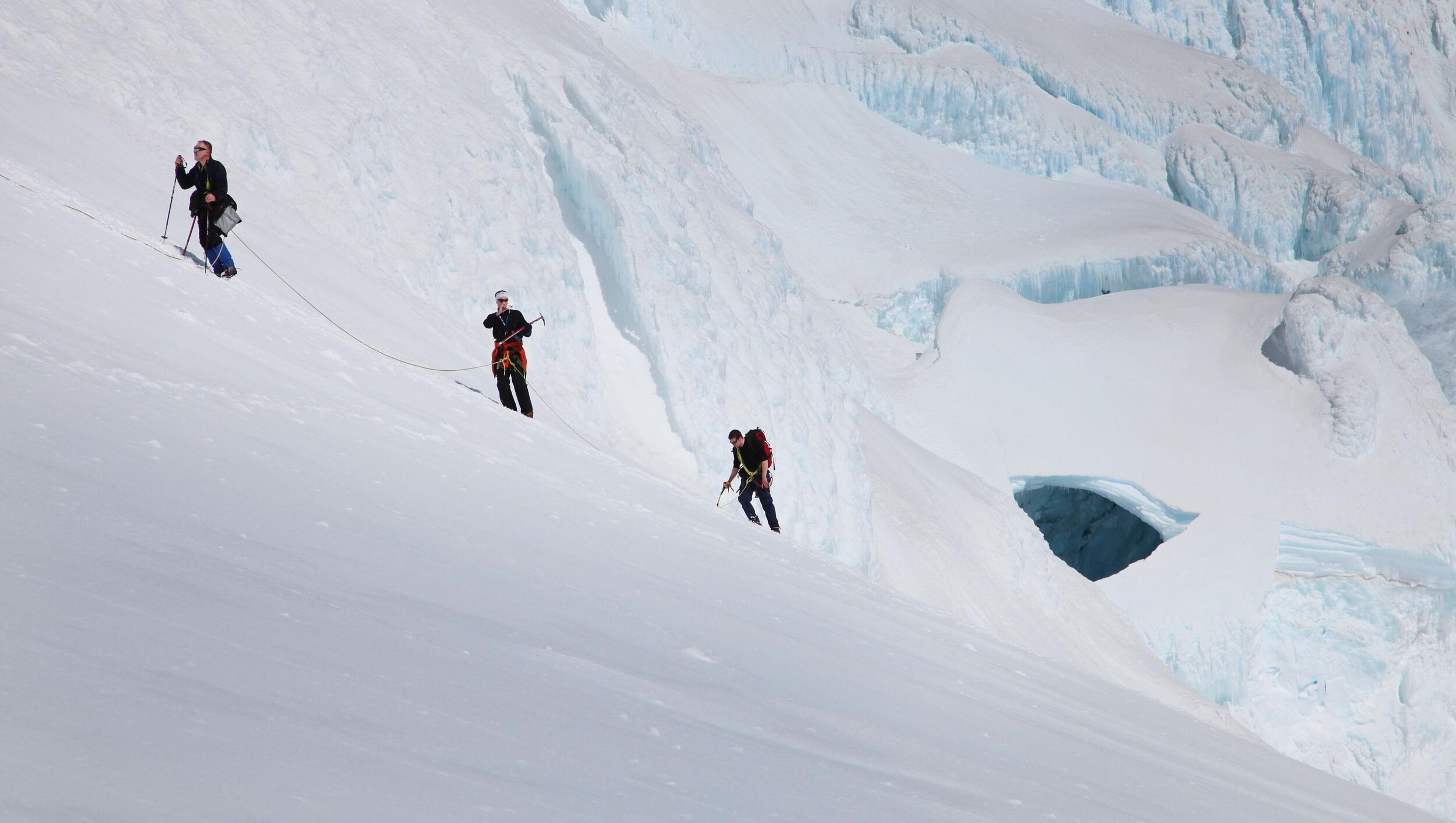 Group of climbers ascending Hvannadalsnjúkur with deep glacial crevasses visible in the background.