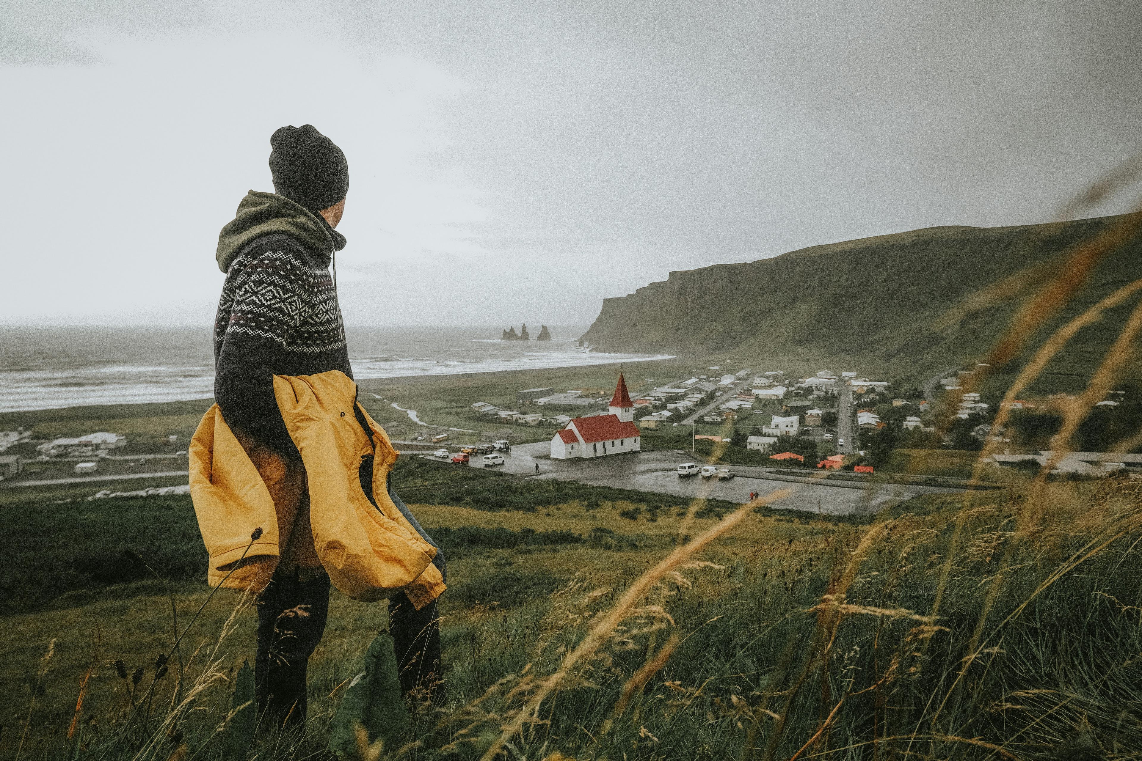  A traveler overlooks Vík village and its iconic red-roofed church, a popular stop on Iceland’s South Coast tour.