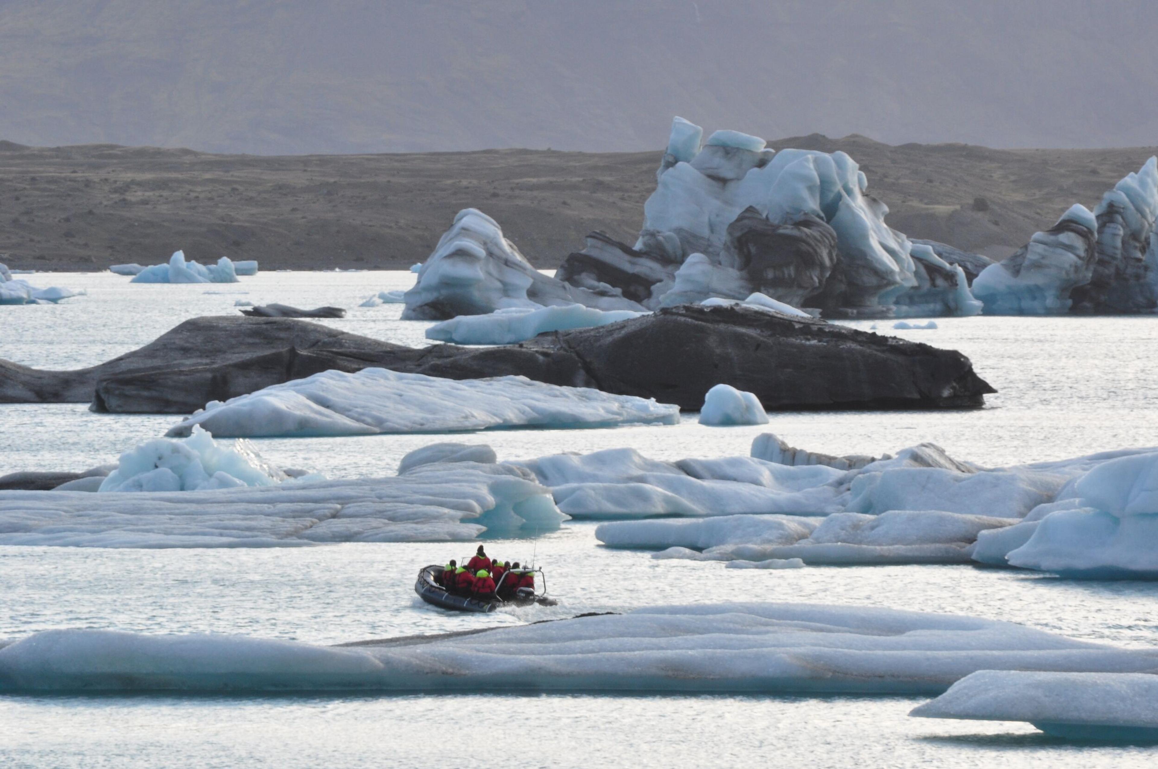 Small zodiac boat speeding trough the iceberg-filled lagoon