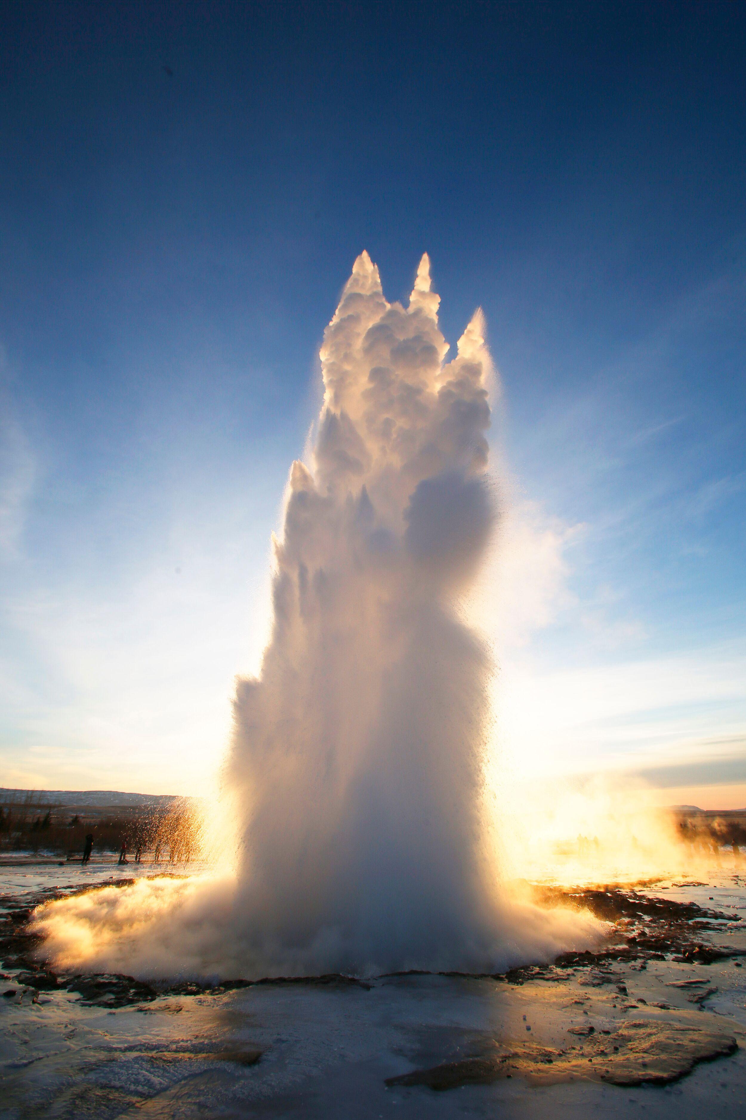 a large geyser is erupting into the air at sunset .
