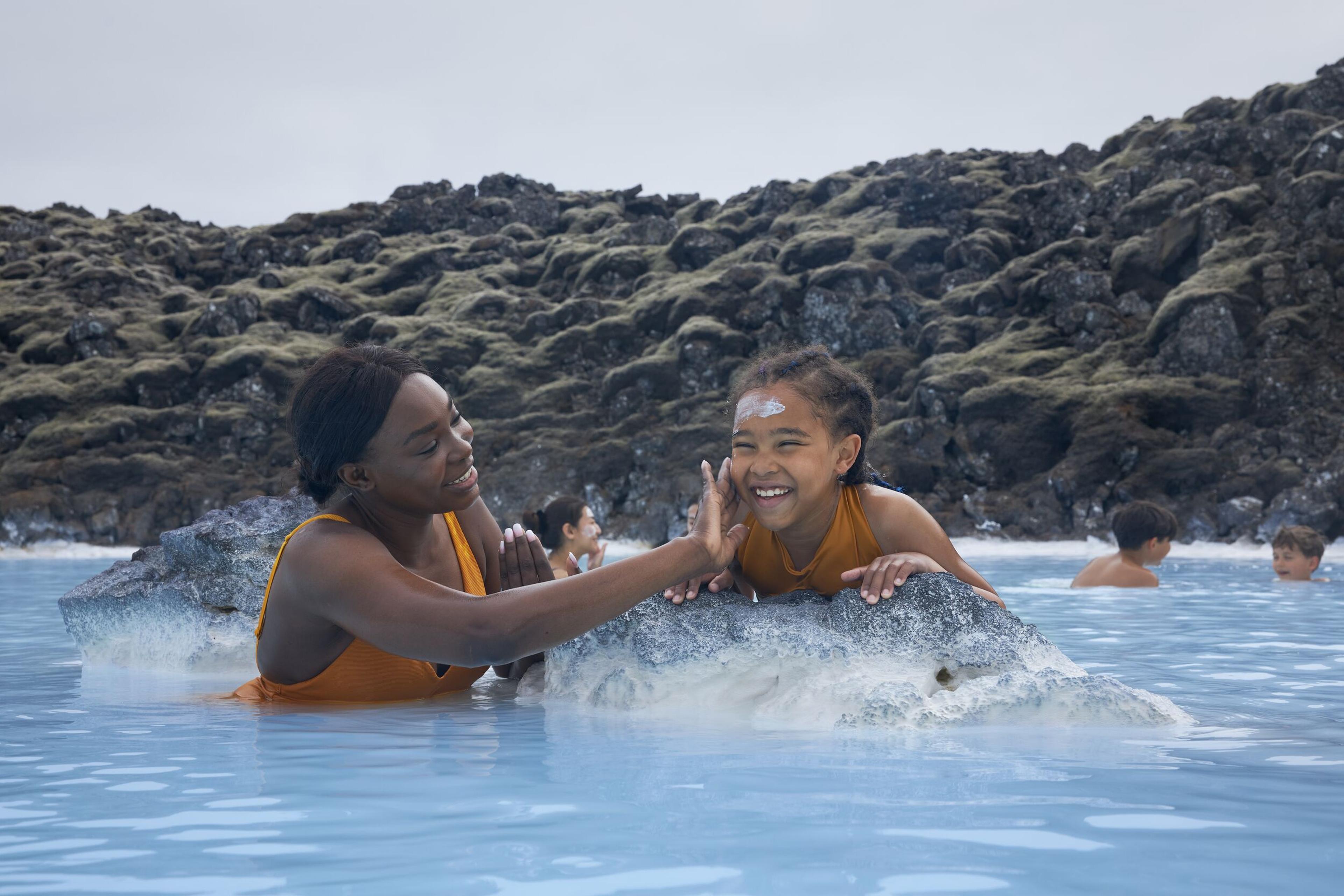 A mother and daughter enjoying the geothermal waters of the Blue Lagoon in Iceland, smiling and playing together.