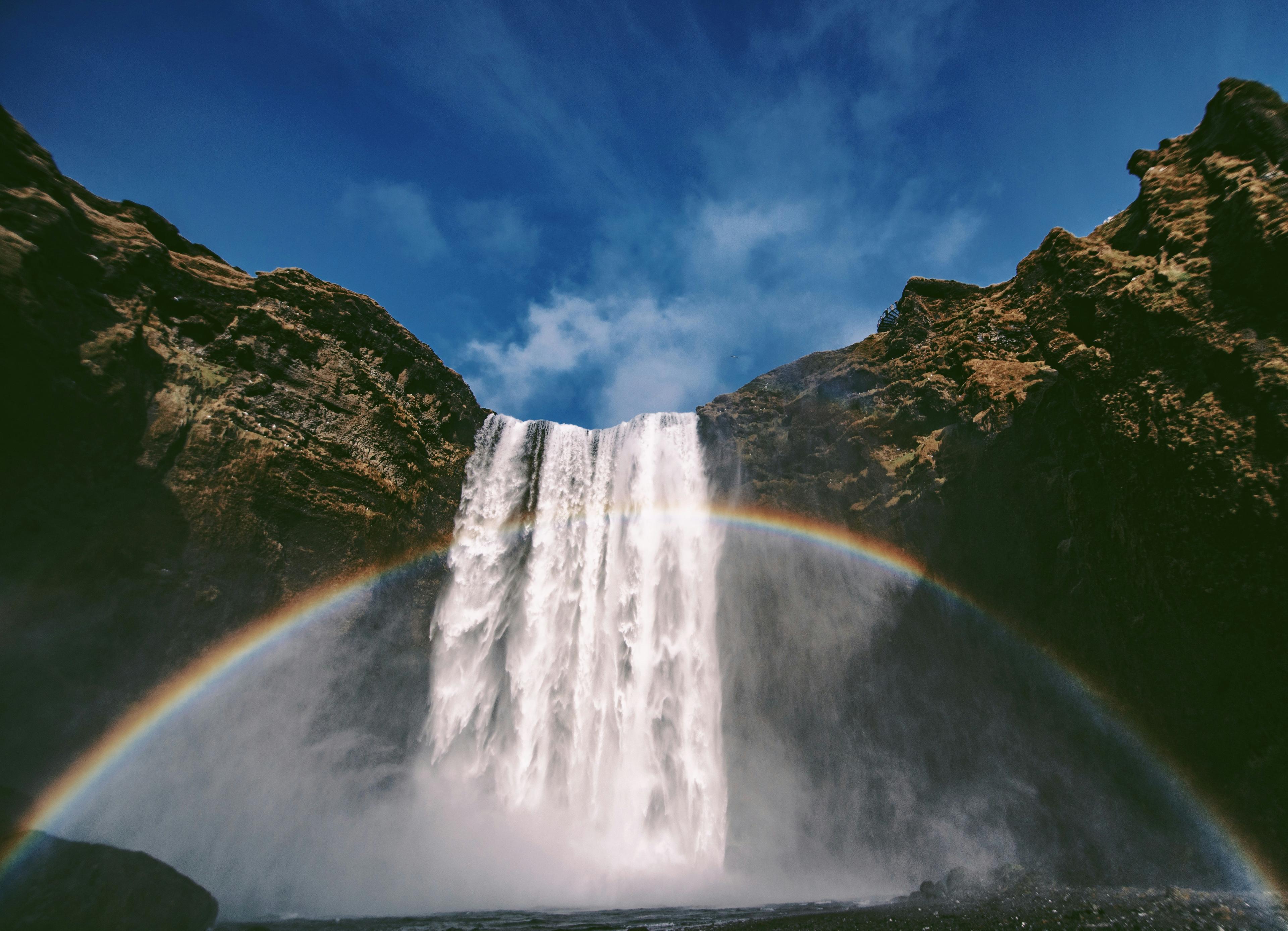 Majestic Skógafoss waterfall cascading down cliffs with a vibrant rainbow arching across the mist