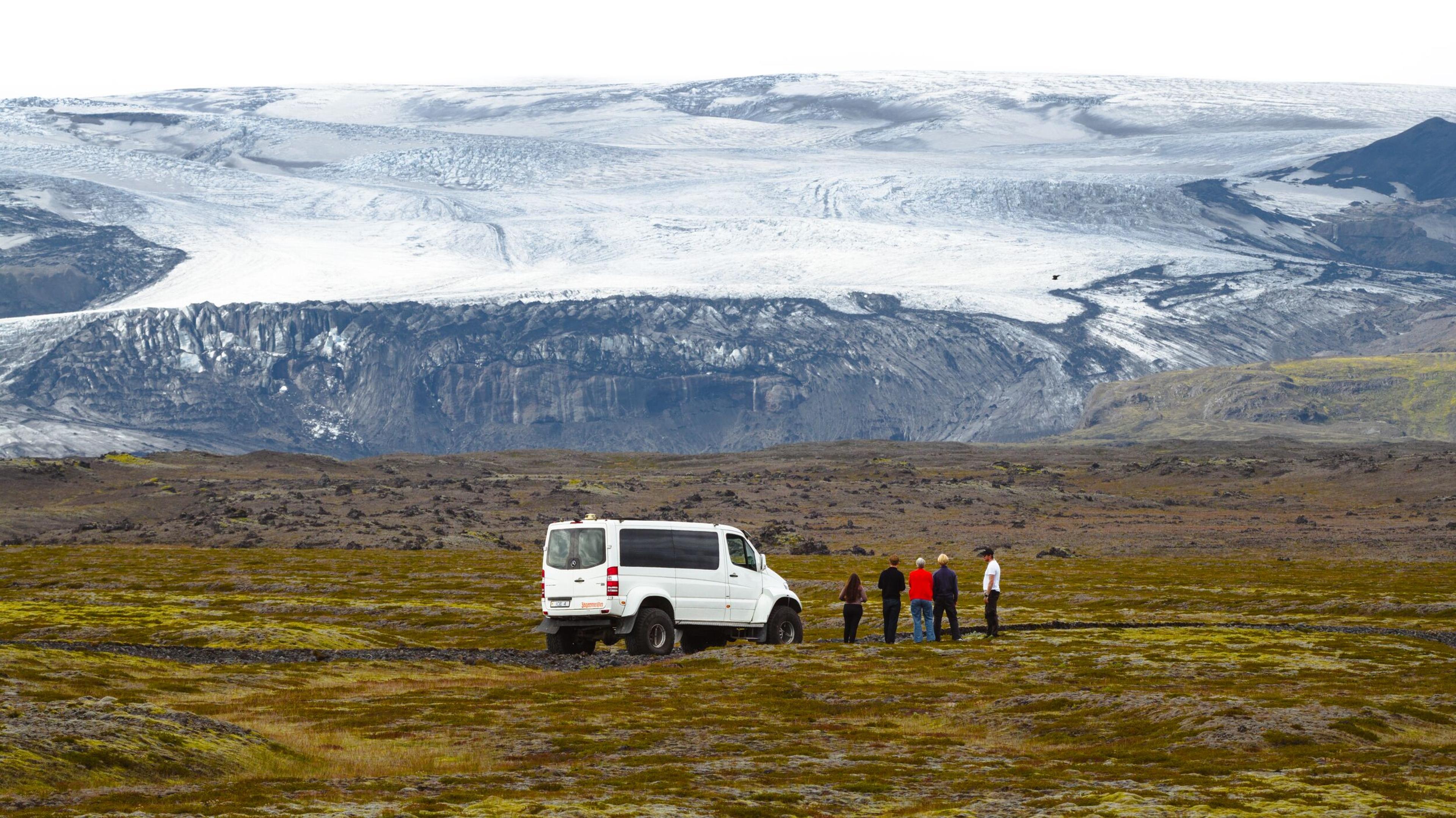 a group of people are standing in front of a white van in a field .