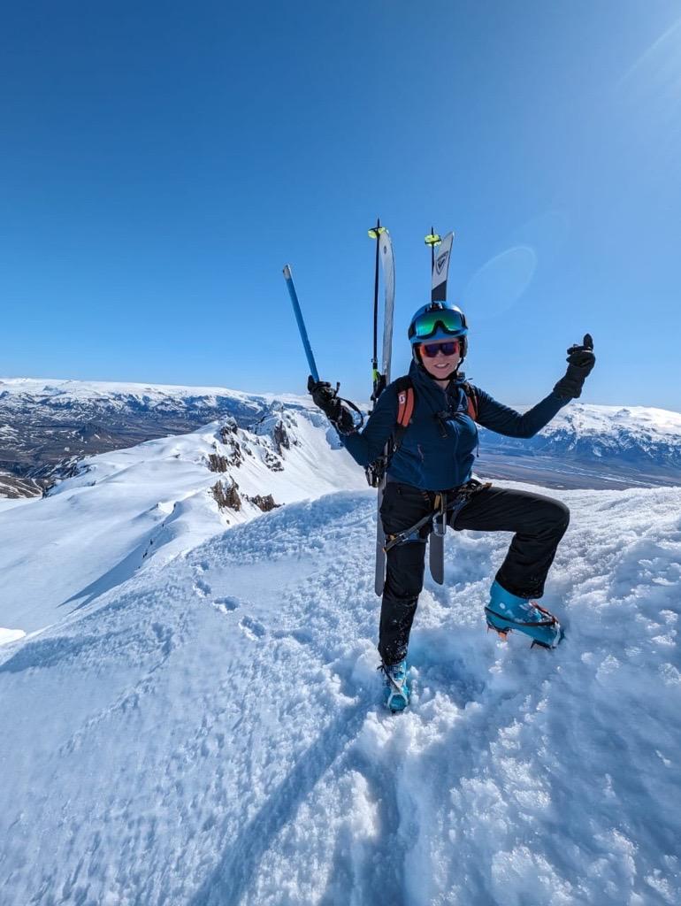 a person is standing on top of a snow covered mountain holding skis .