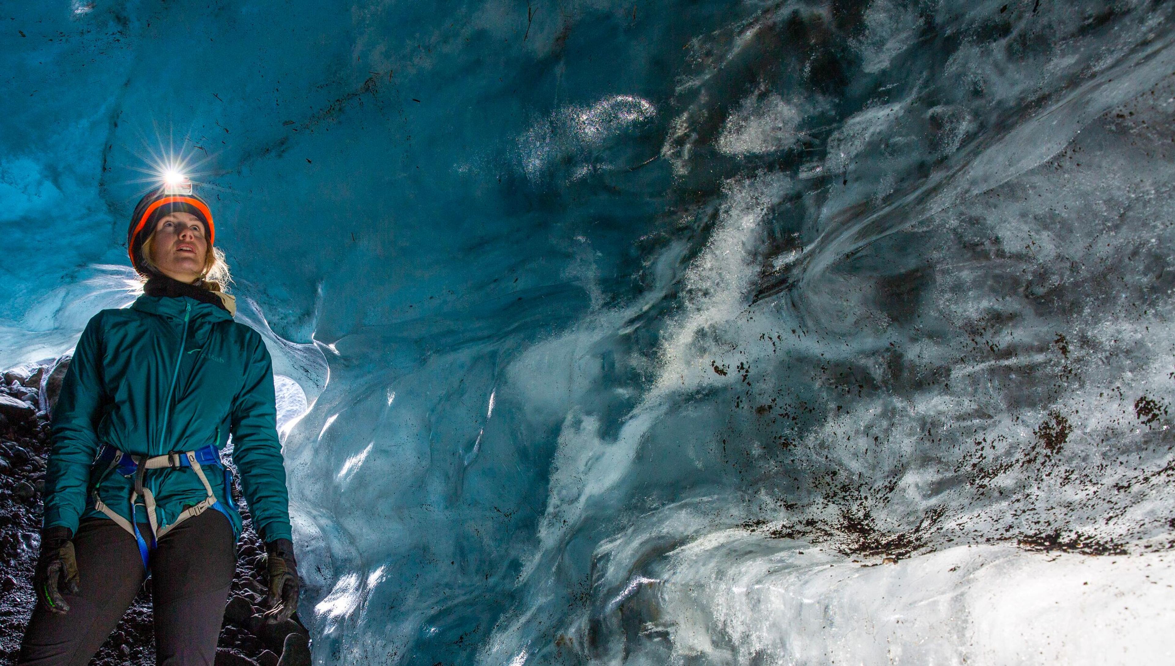 a woman is standing inside of an ice cave .