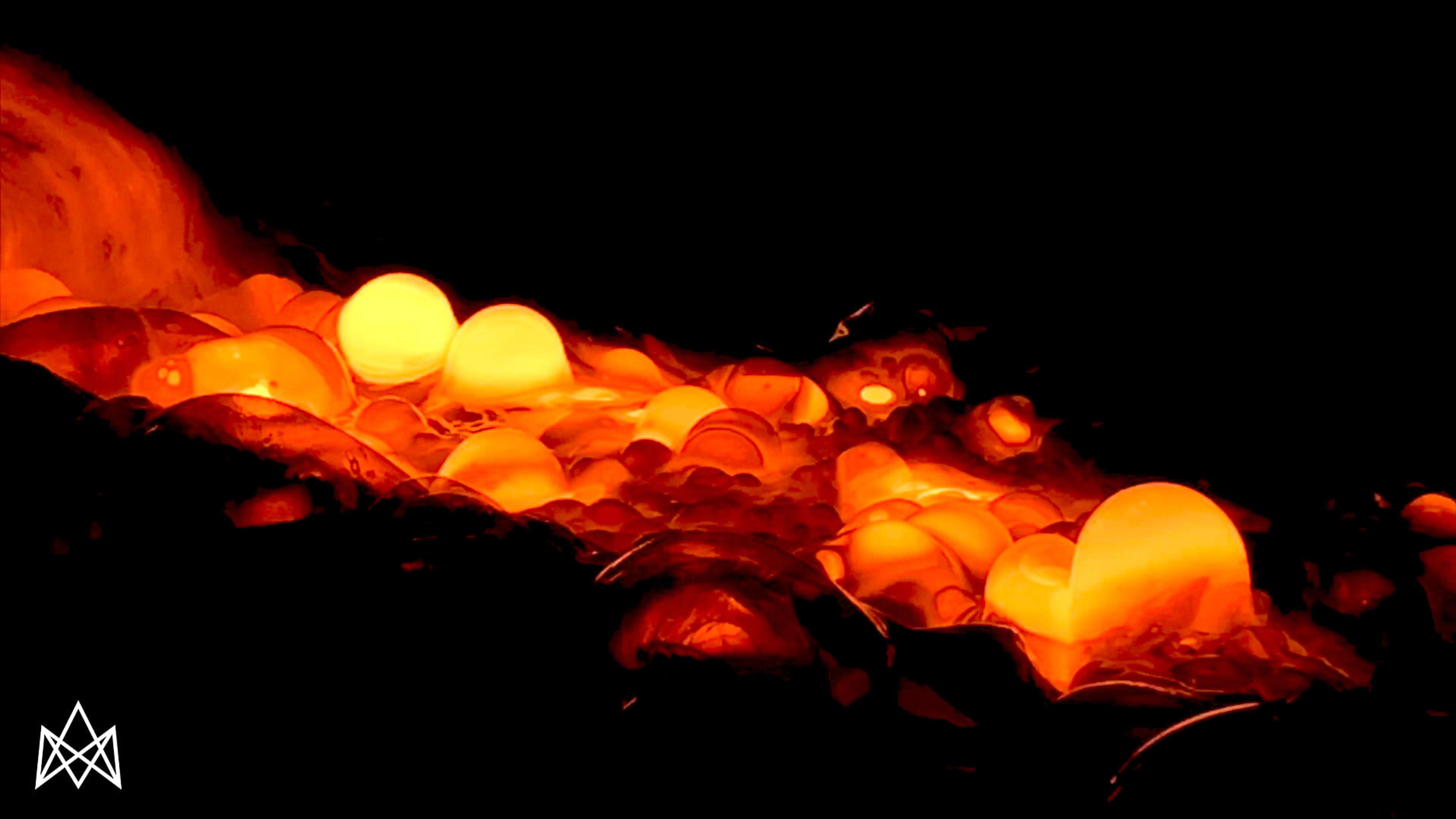 Glowing orange and yellow molten material with embedded spheres on a dark background.