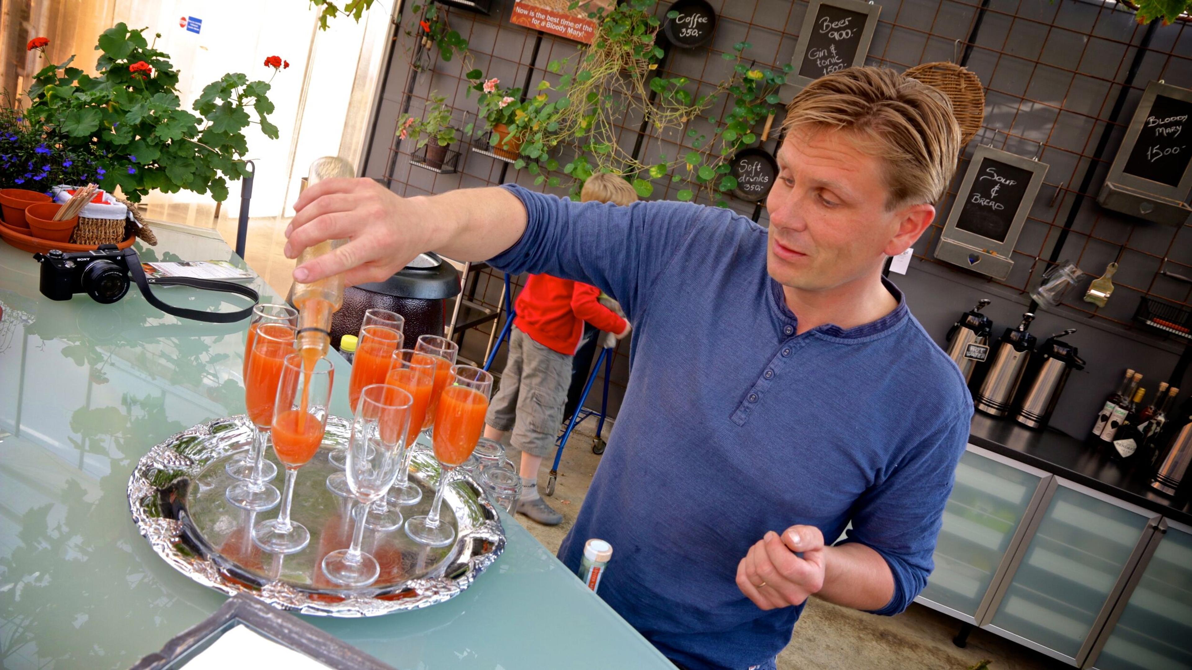 Waiter serving tomato juice based drinks at Fridheimar greenhouse in Iceland