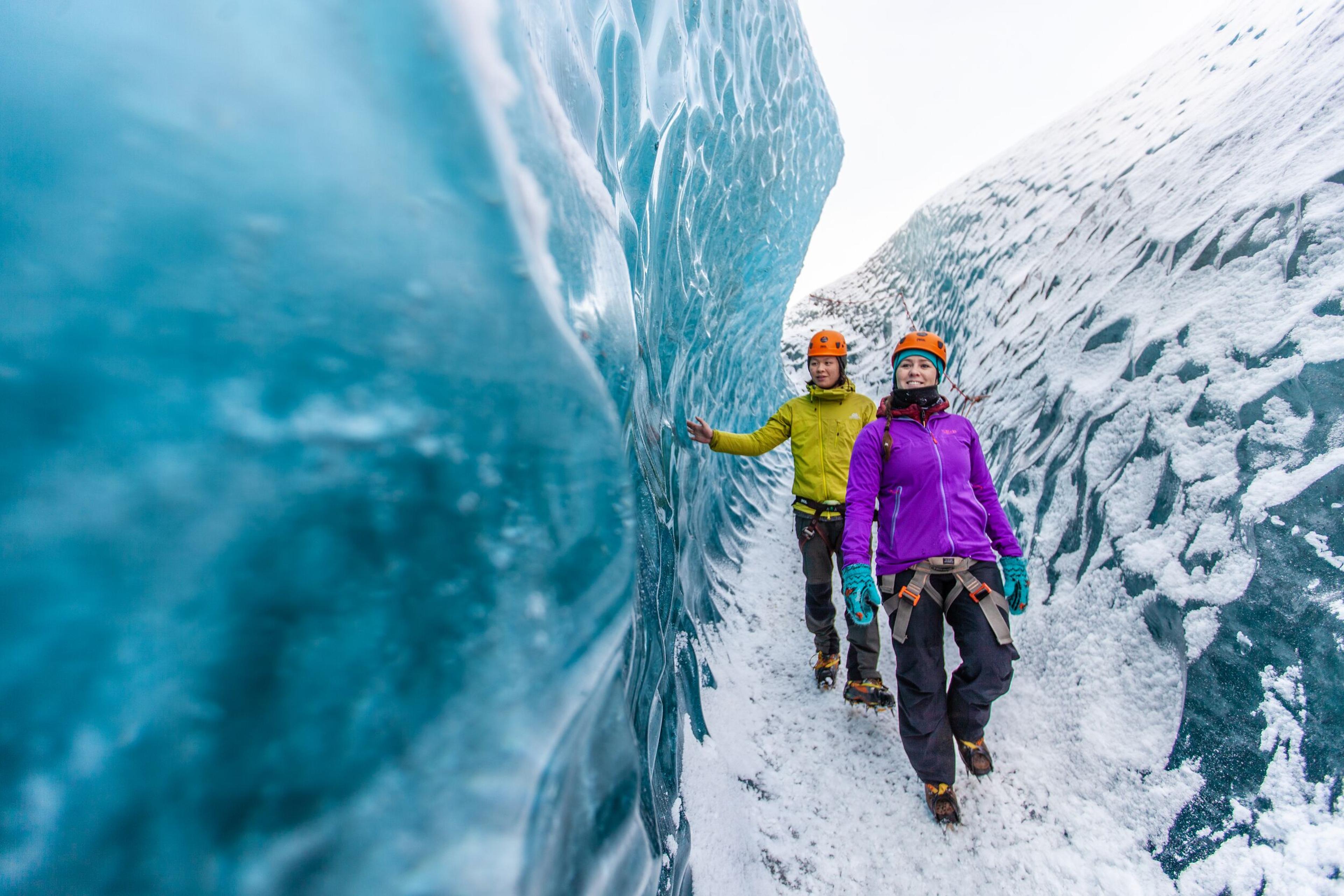 a man and a woman are walking through an ice cave .