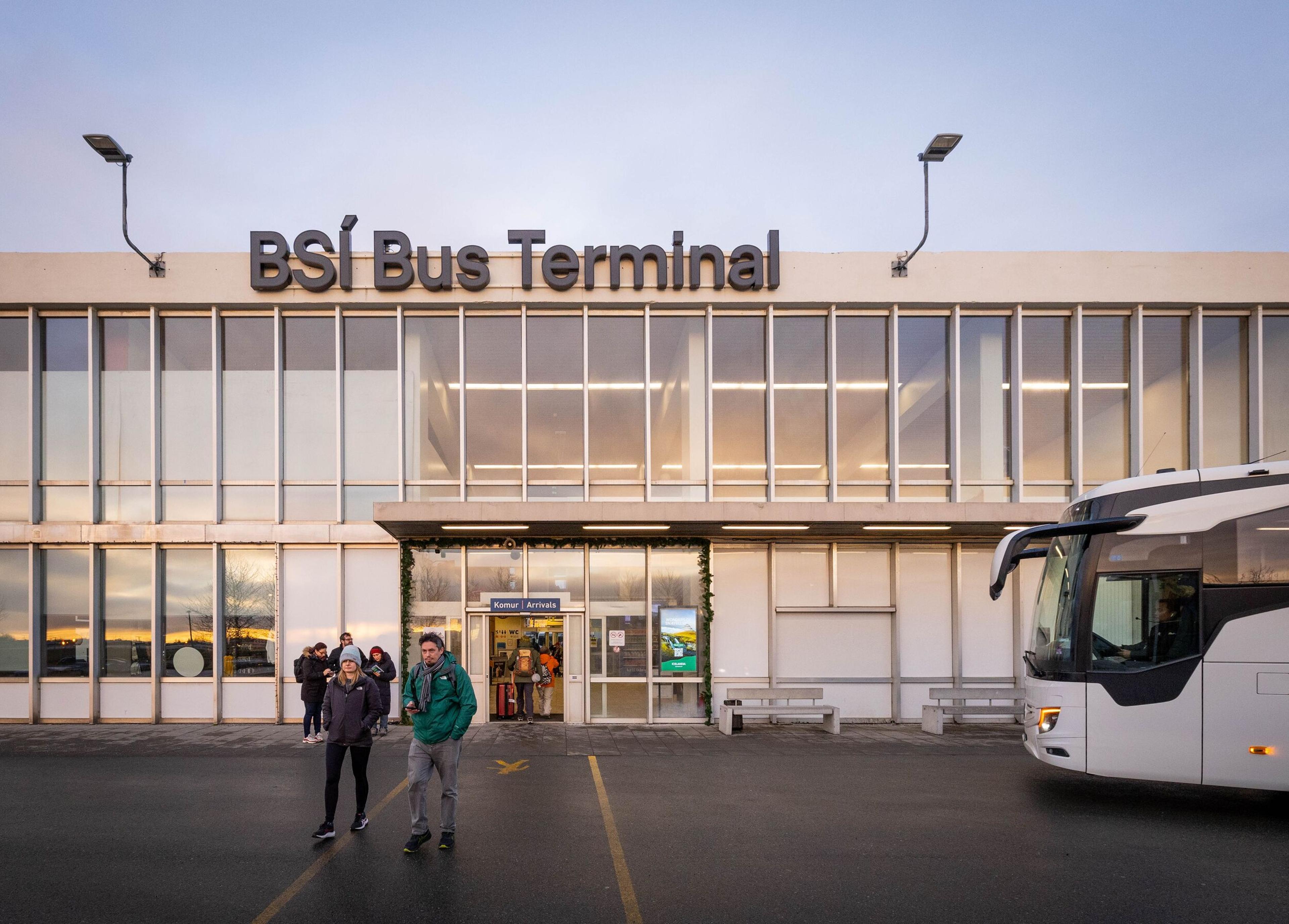 BSI Bus Terminal building with people walking outside and a white bus parked nearby.