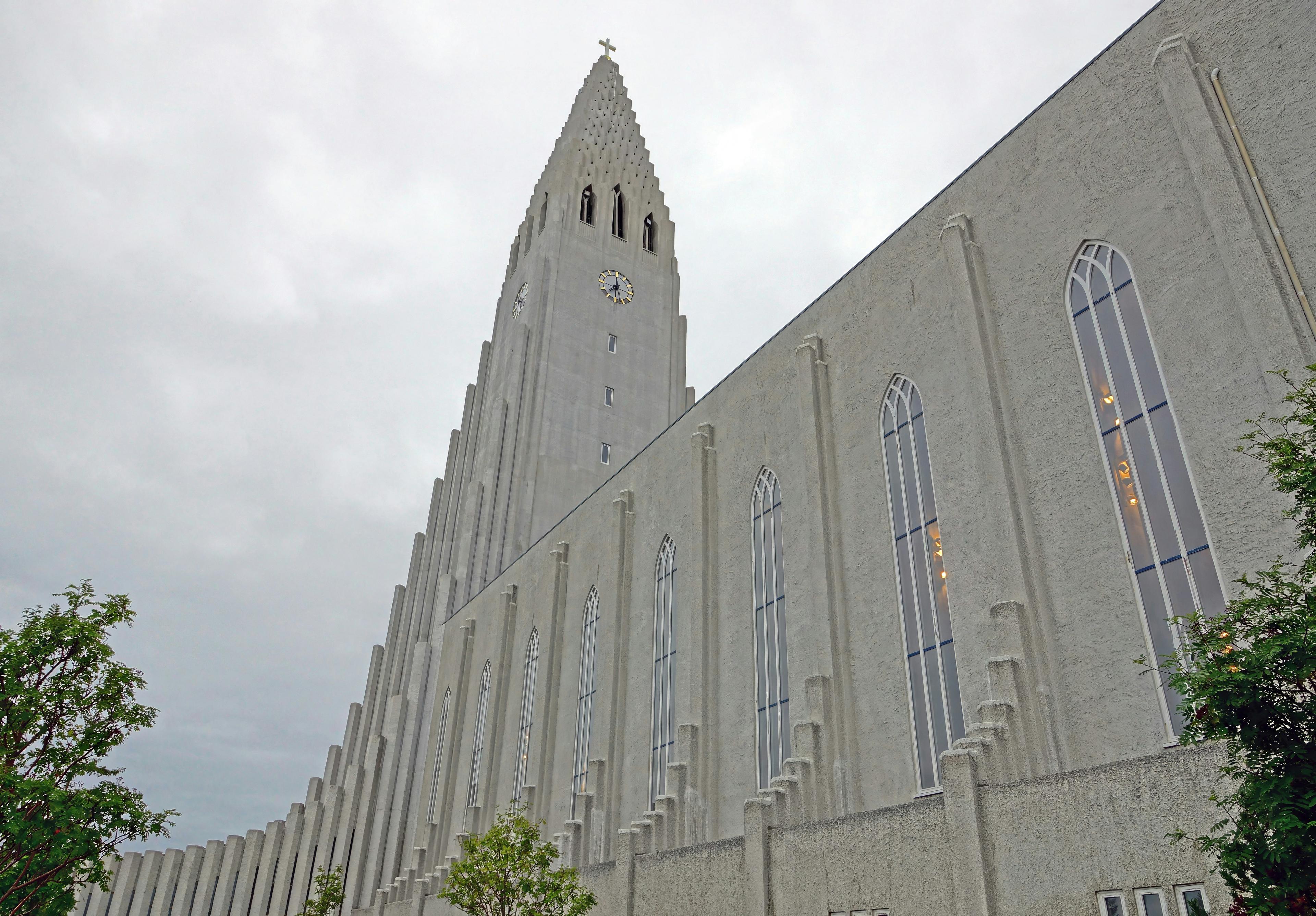 Exterior view of Hallgrímskirkja church showcasing its iconic stepped concrete facade and tall spire under a cloudy sky.