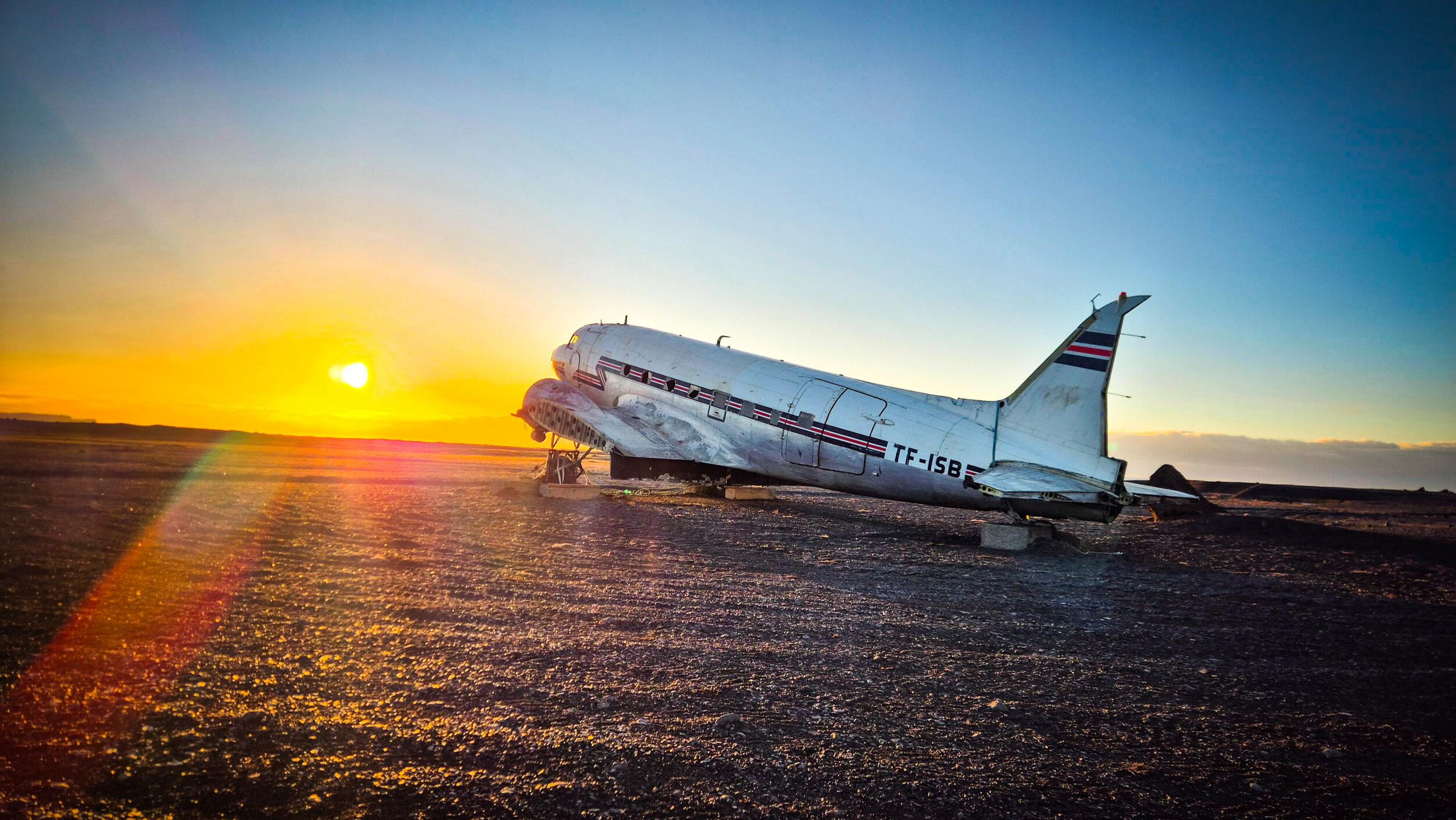 The TF-ISB DC-3 plane wreck on a desolate plain under a golden sunset.