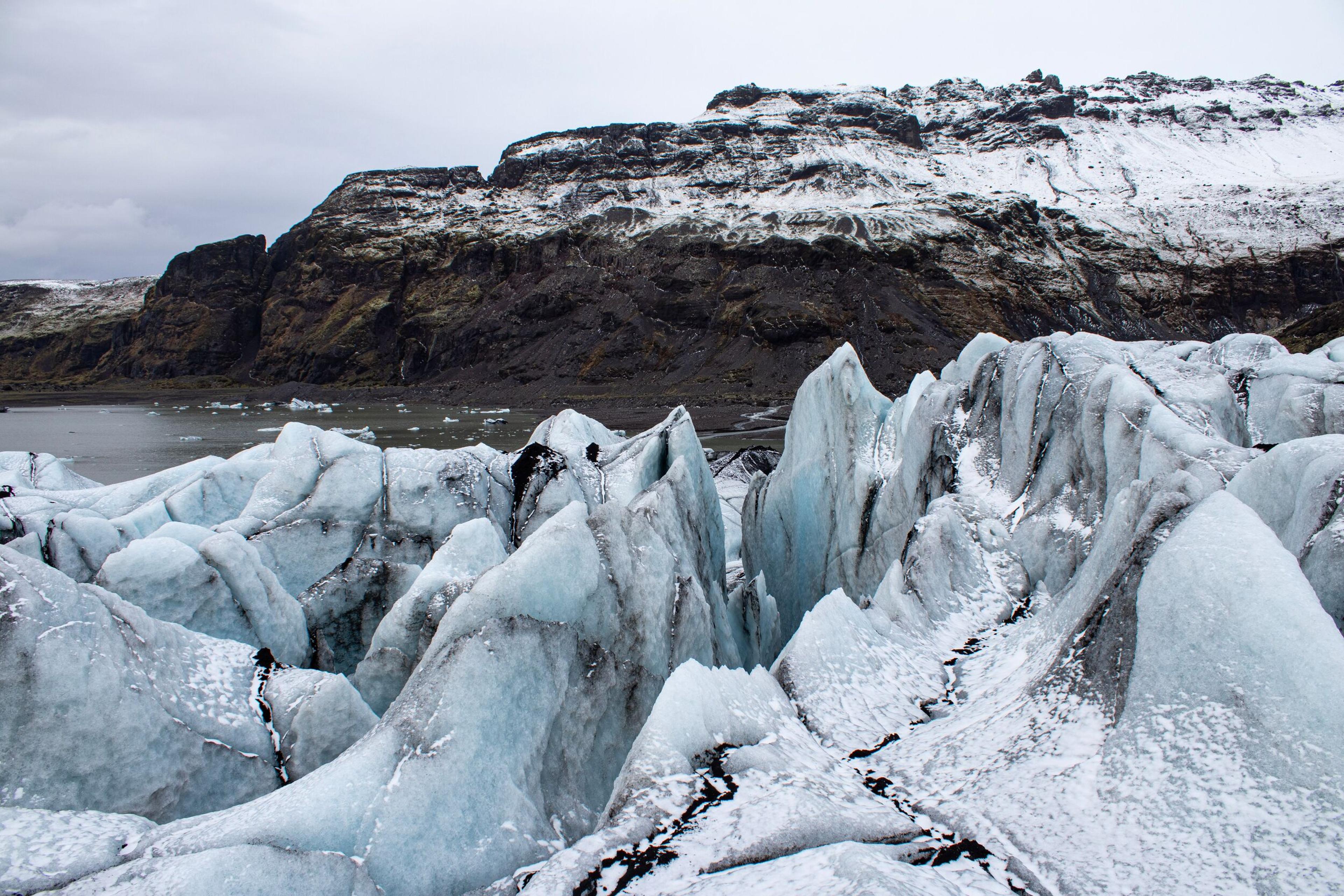 a large iceberg is surrounded by snow and mountains .