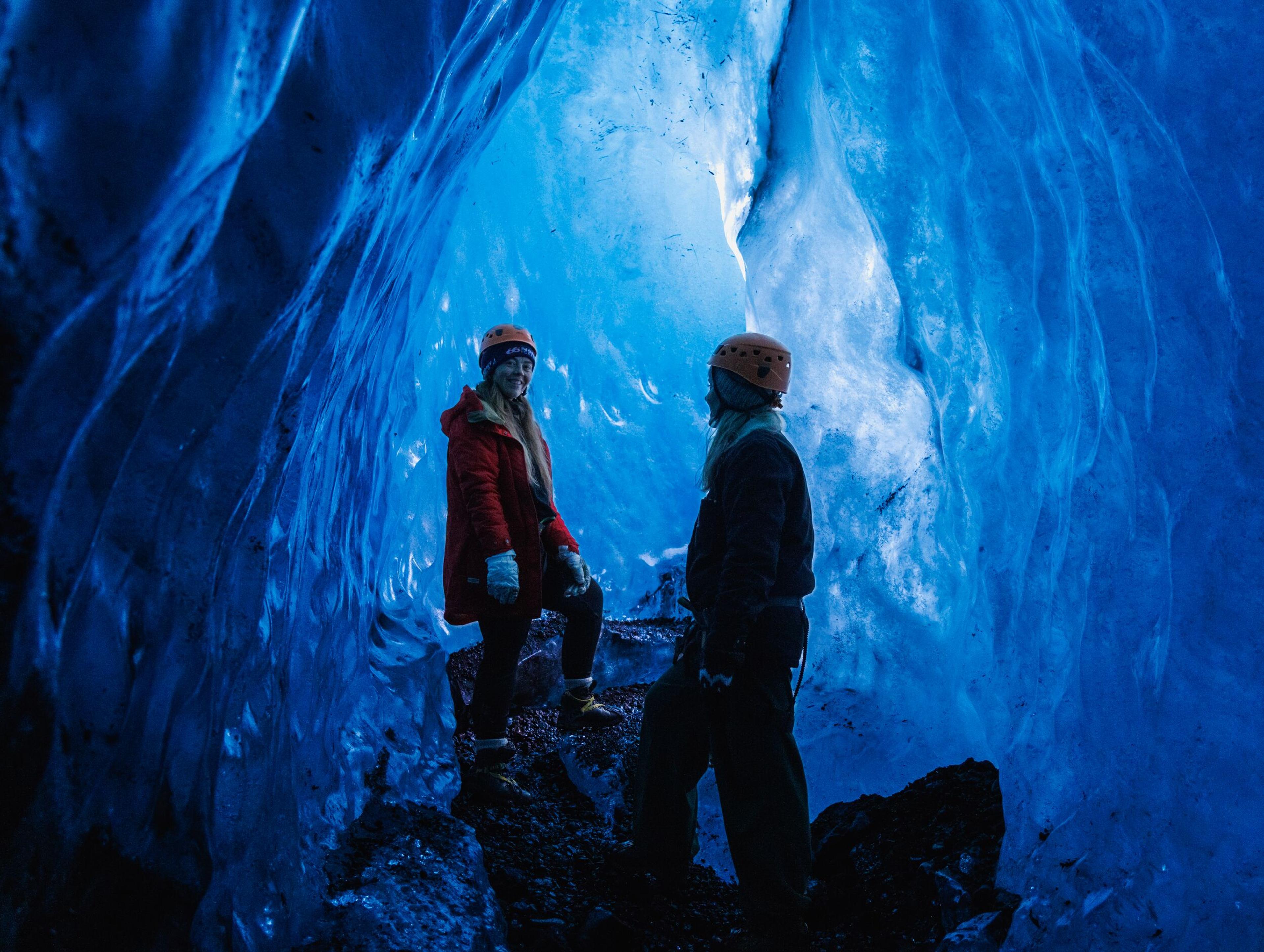 A person poses inside a glowing blue ice cave.