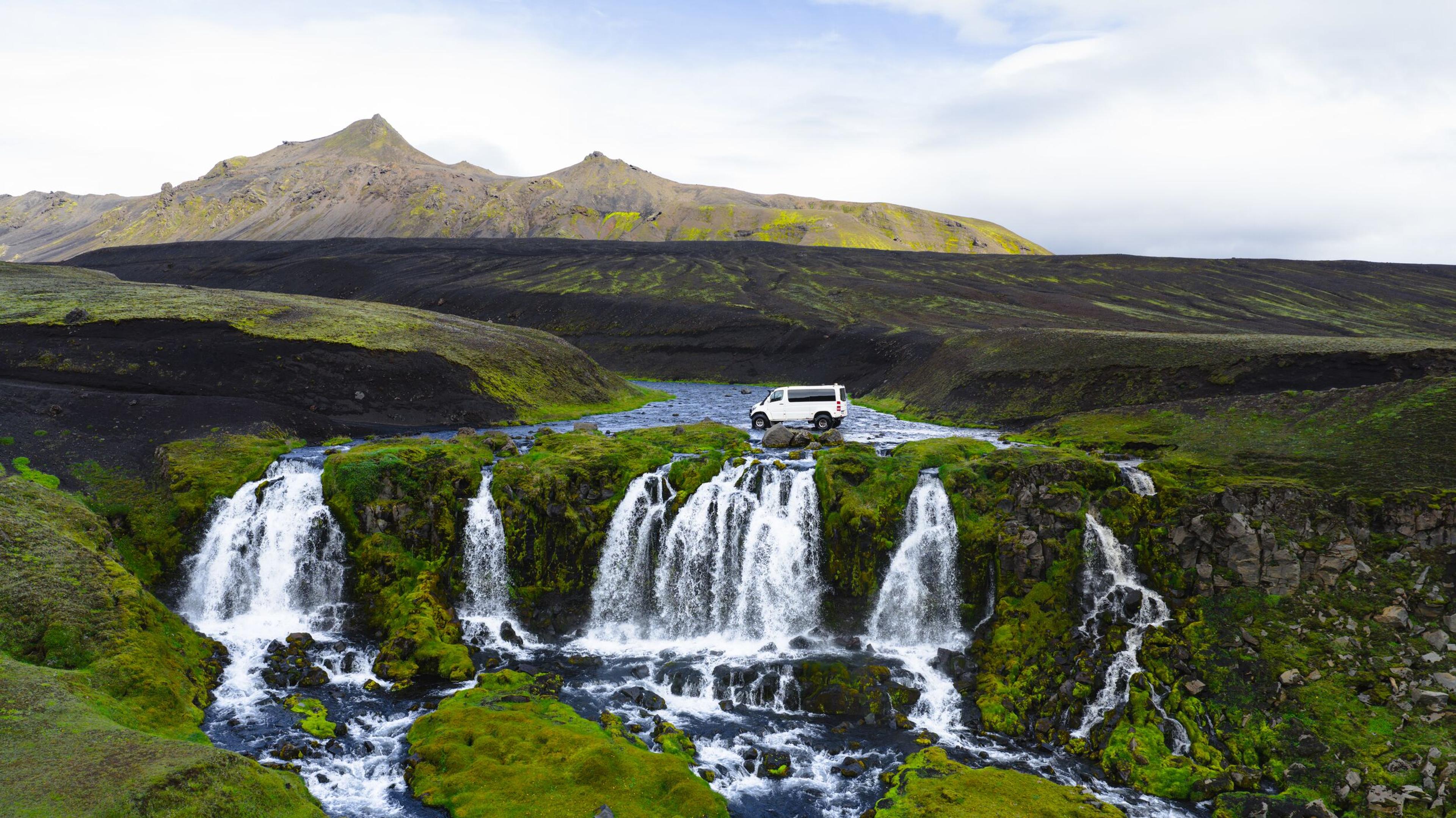 a white van is parked on top of a waterfall .
