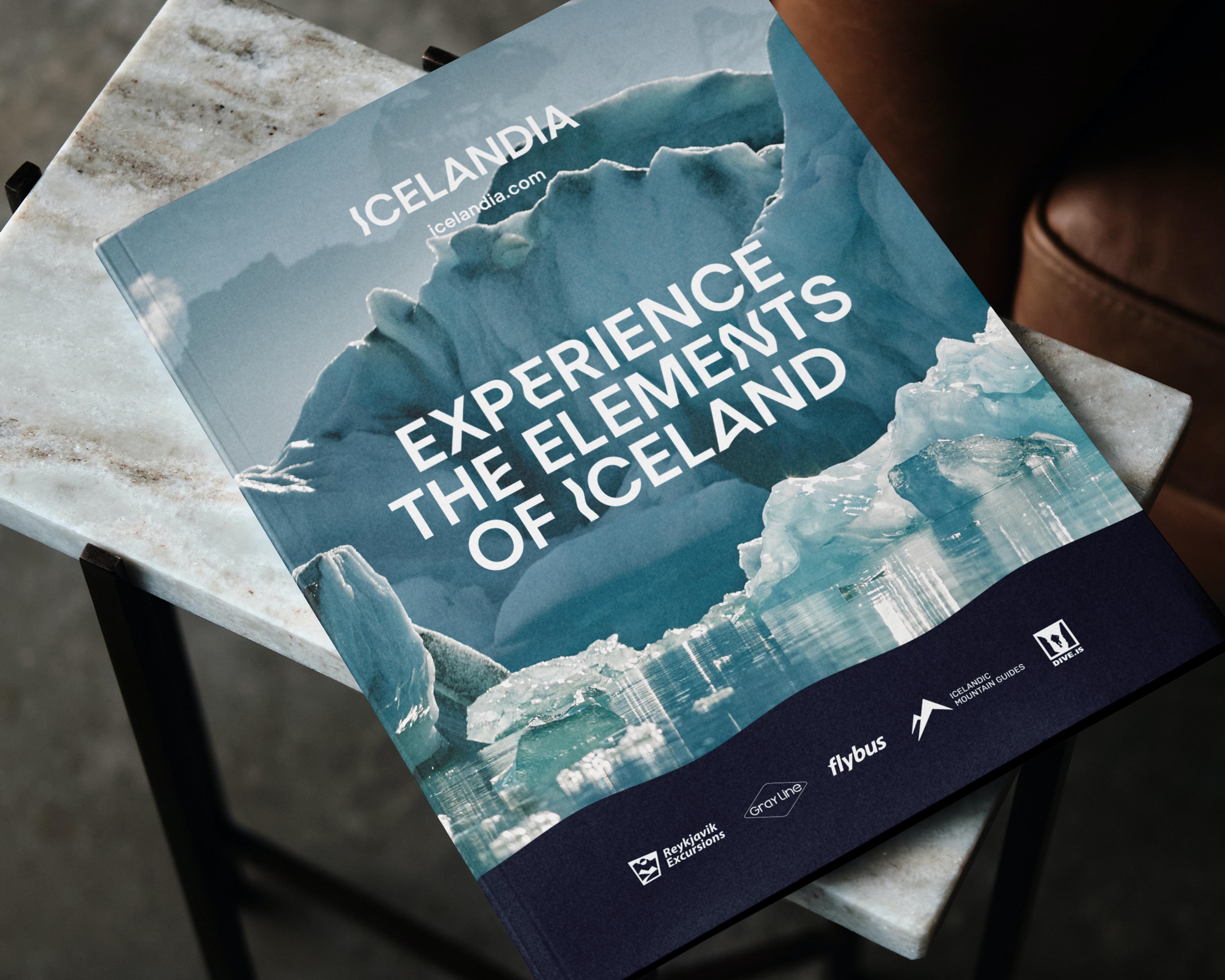 A brochure for Icelandia titled "Experience the Elements of Iceland" featuring a glacial landscape, resting on a marble table.