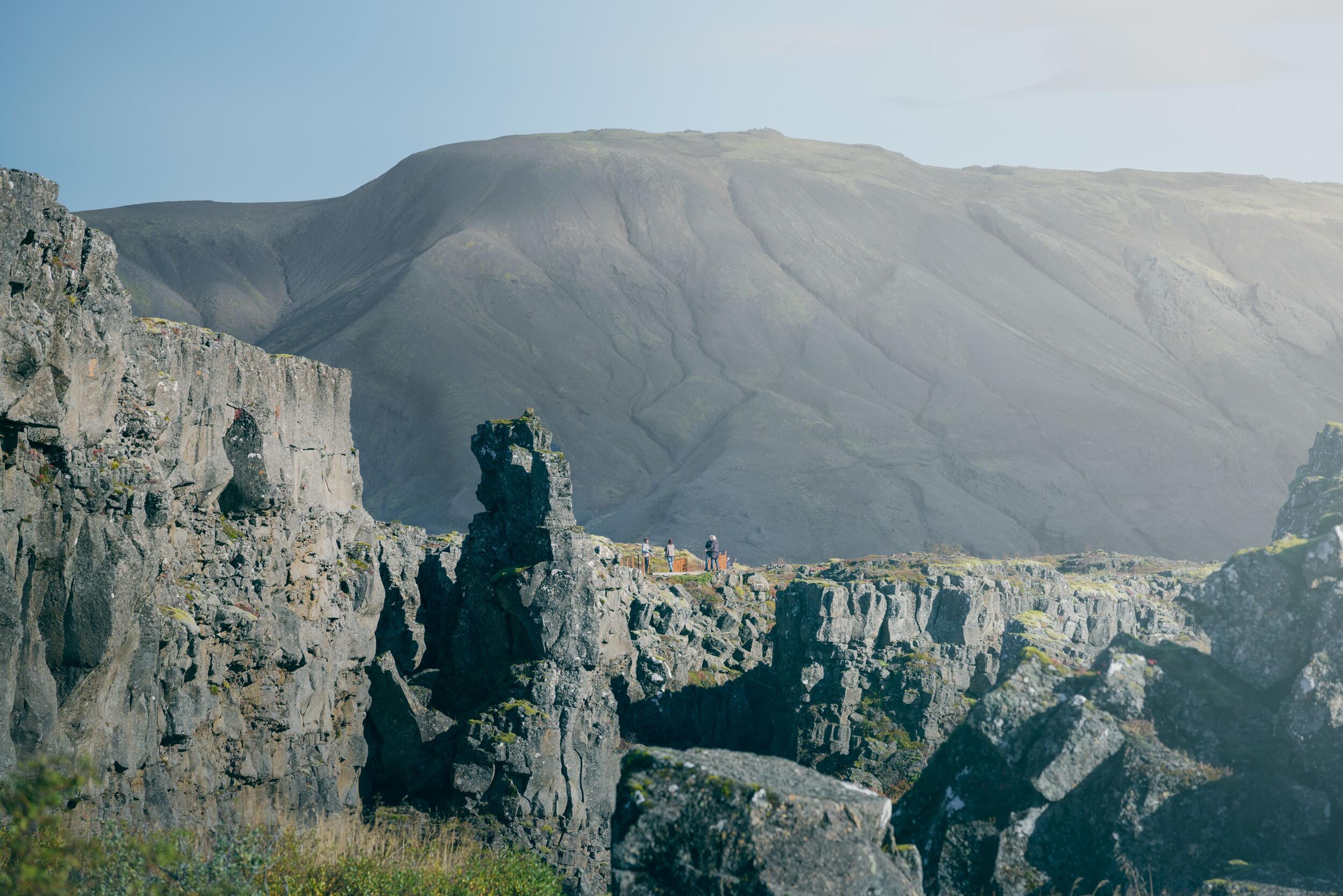 Rugged cliffs and rock formations in Thingvellir National Park with a mountainous backdrop.