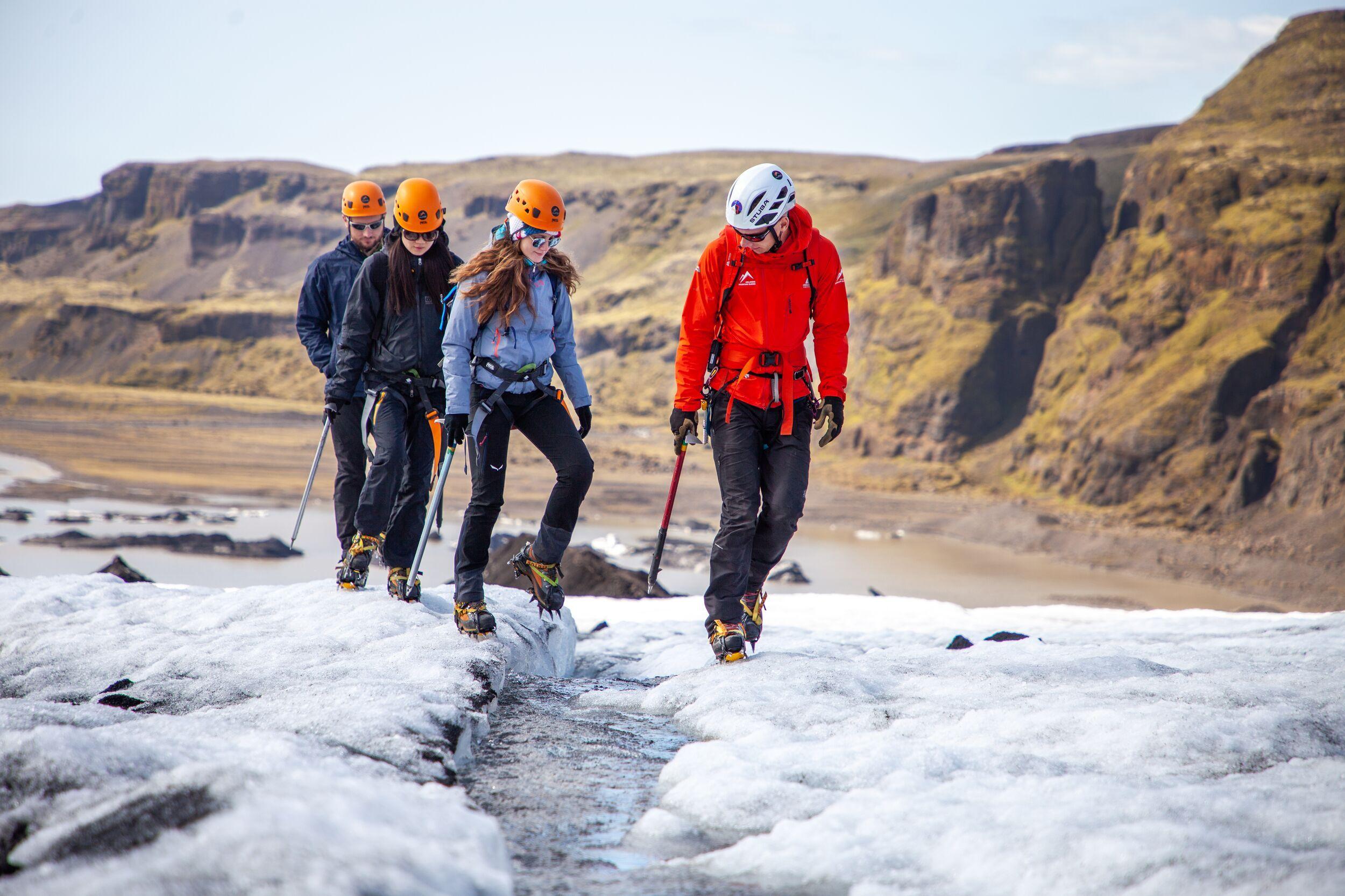 a group of people are walking on top of a glacier .
