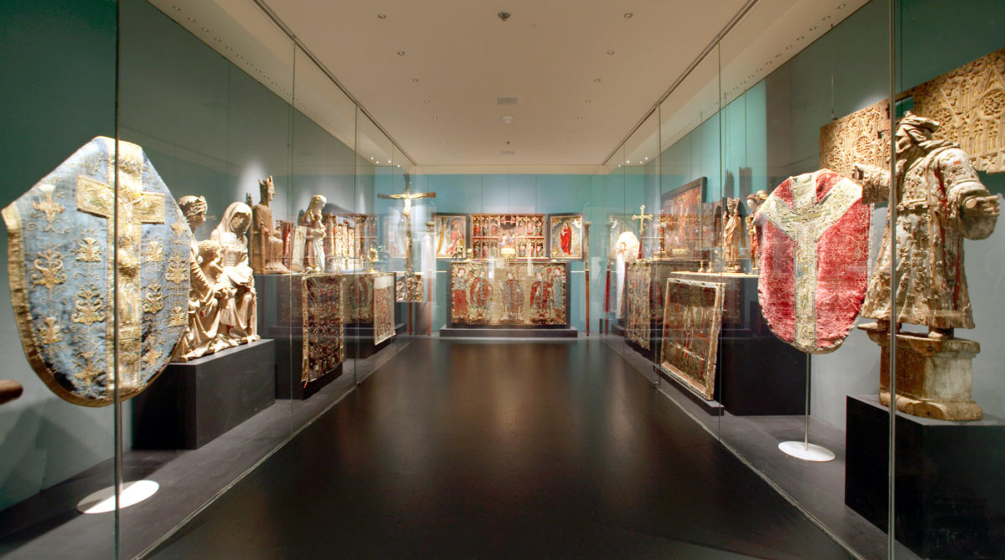 Exhibit of historic religious artifacts and decorations in a well-lit gallery with glass display cases.