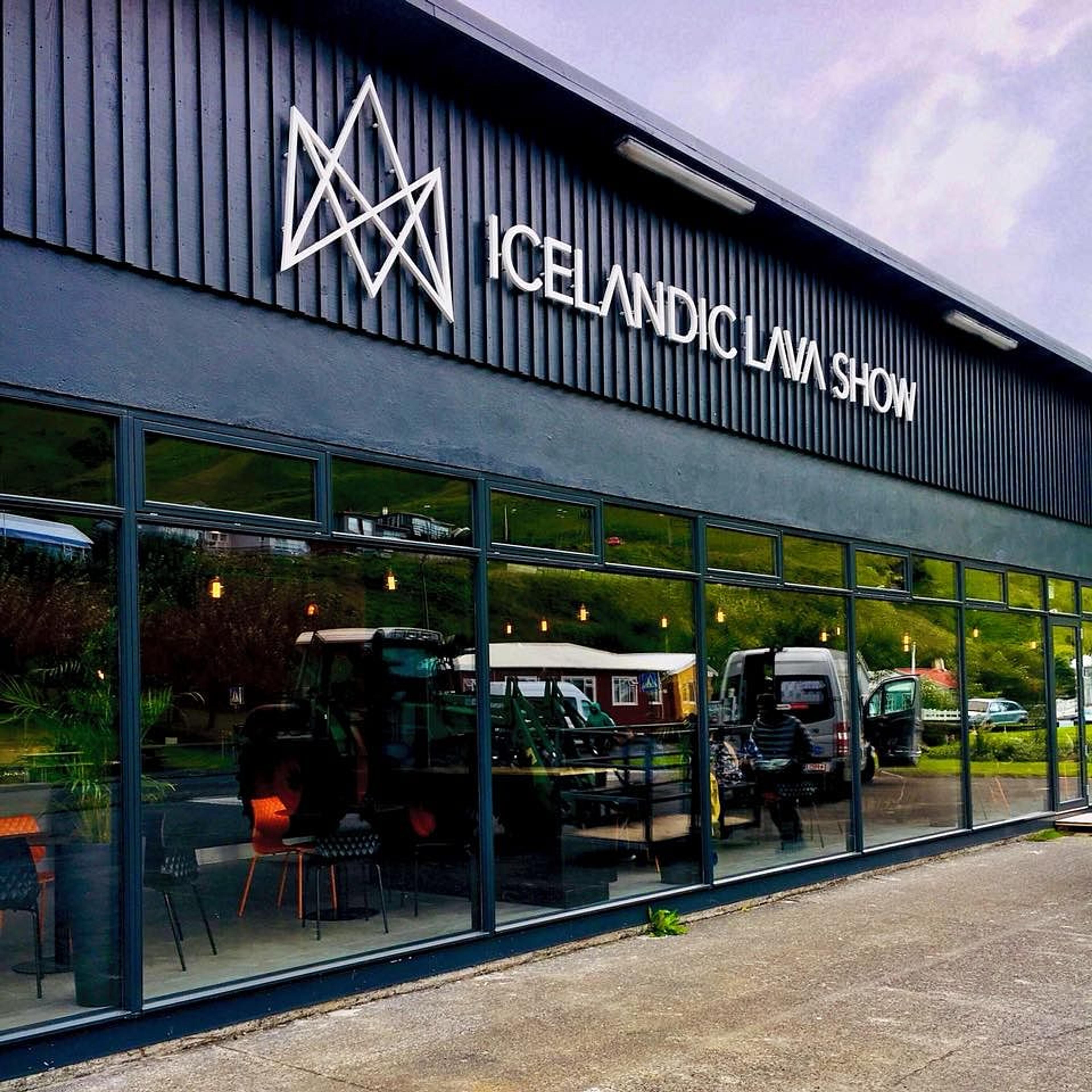 Exterior of the Icelandic Lava Show building, a dark structure with a white sign and large reflective windows.