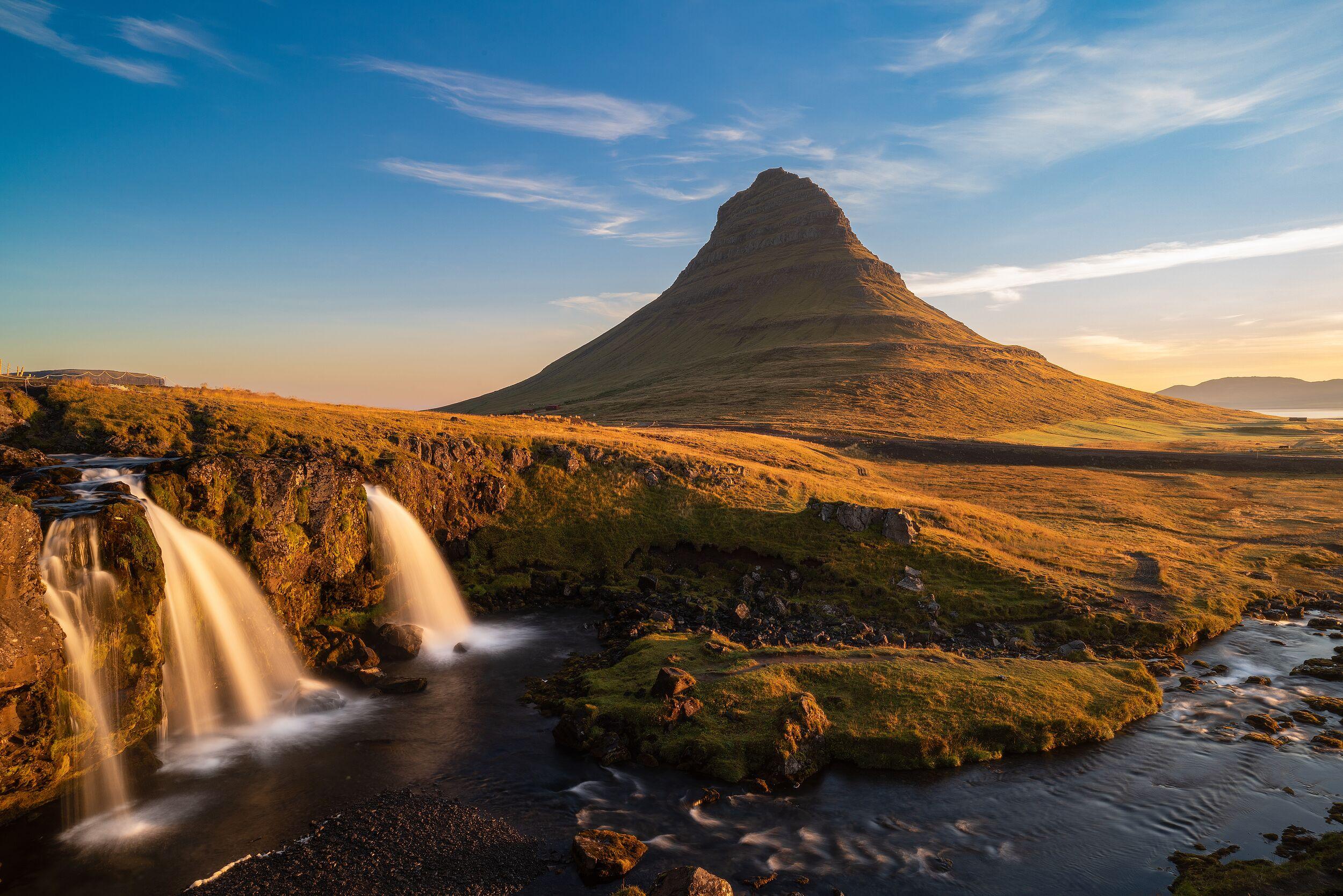 Kirkjufell mountain and Kirkjufellsfoss waterfalls bathed in golden light.