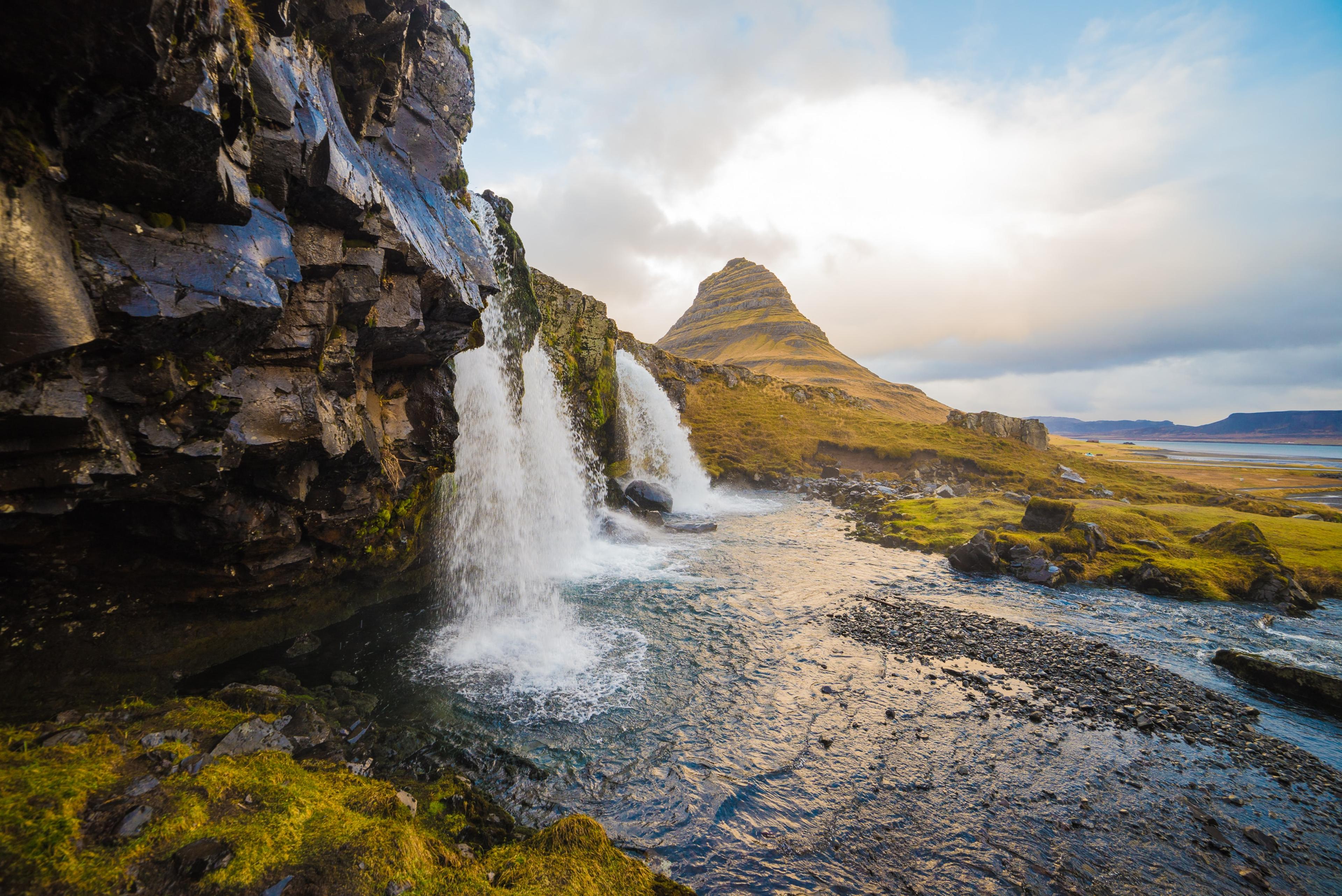 "Spectacular waterfalls cascading with the iconic Kirkjufell mountain as a breathtaking backdrop