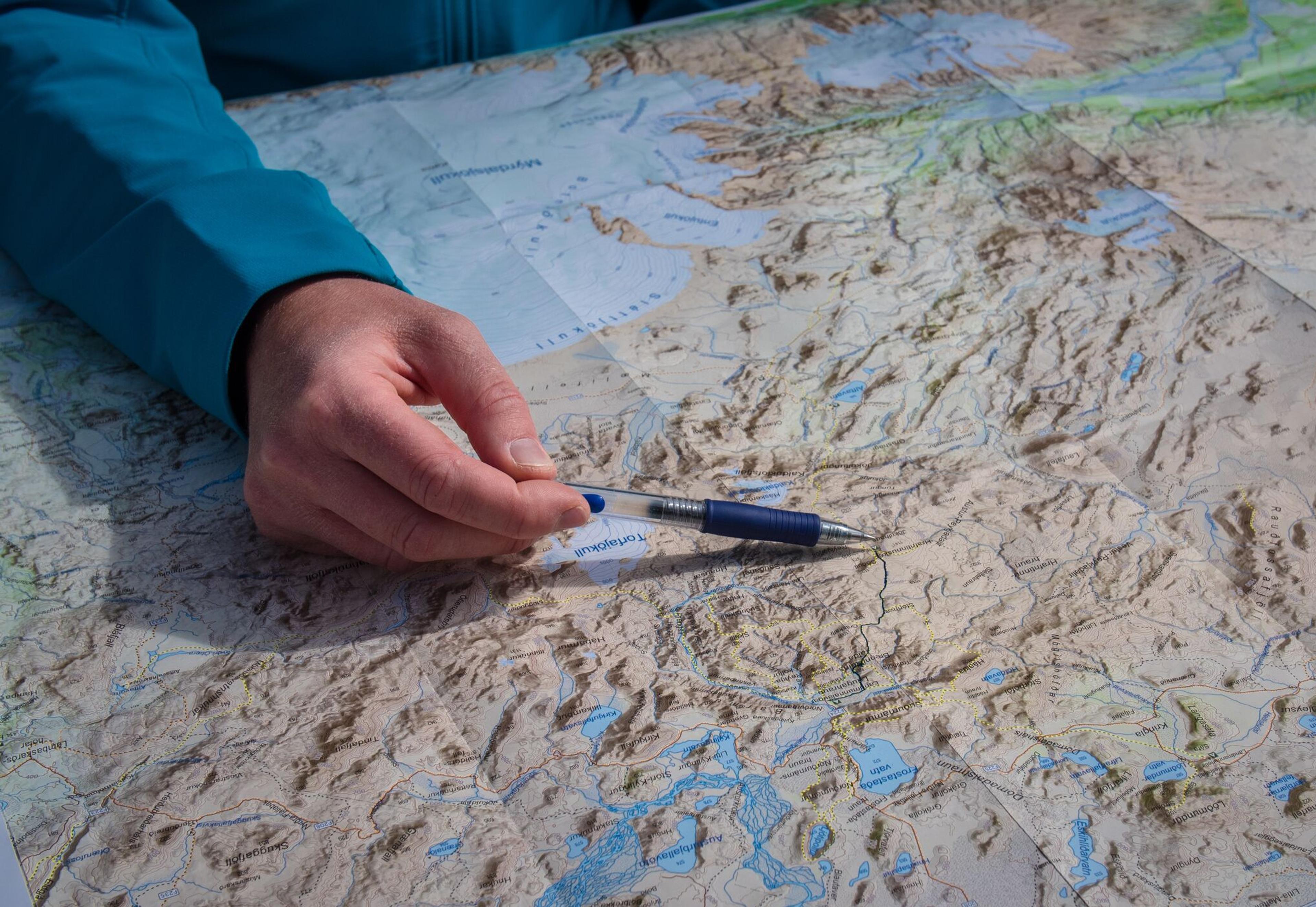 A person with a pen pointing at a map of Iceland.
