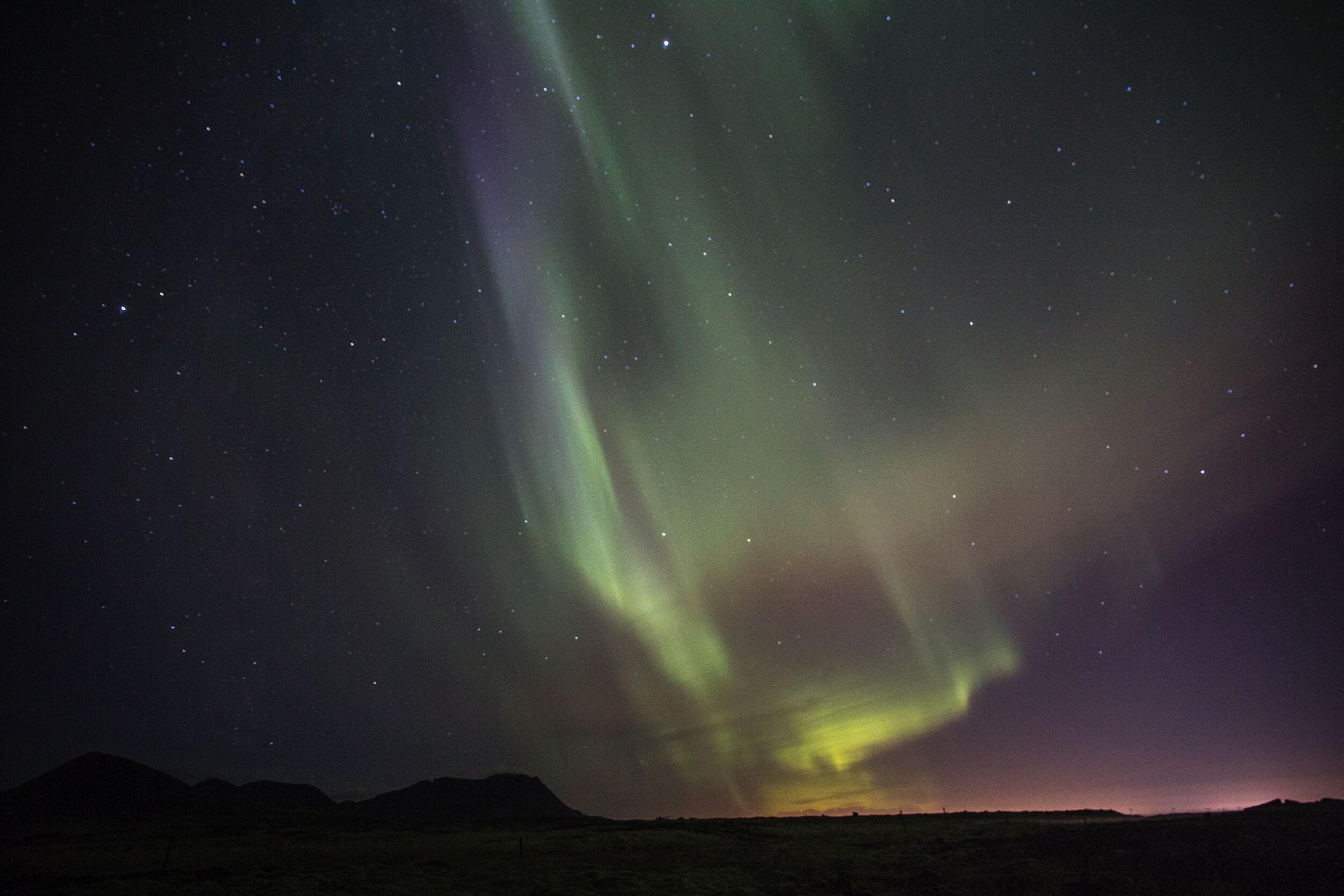 Northern lights dancing ovar a mountain landscape in Iceland