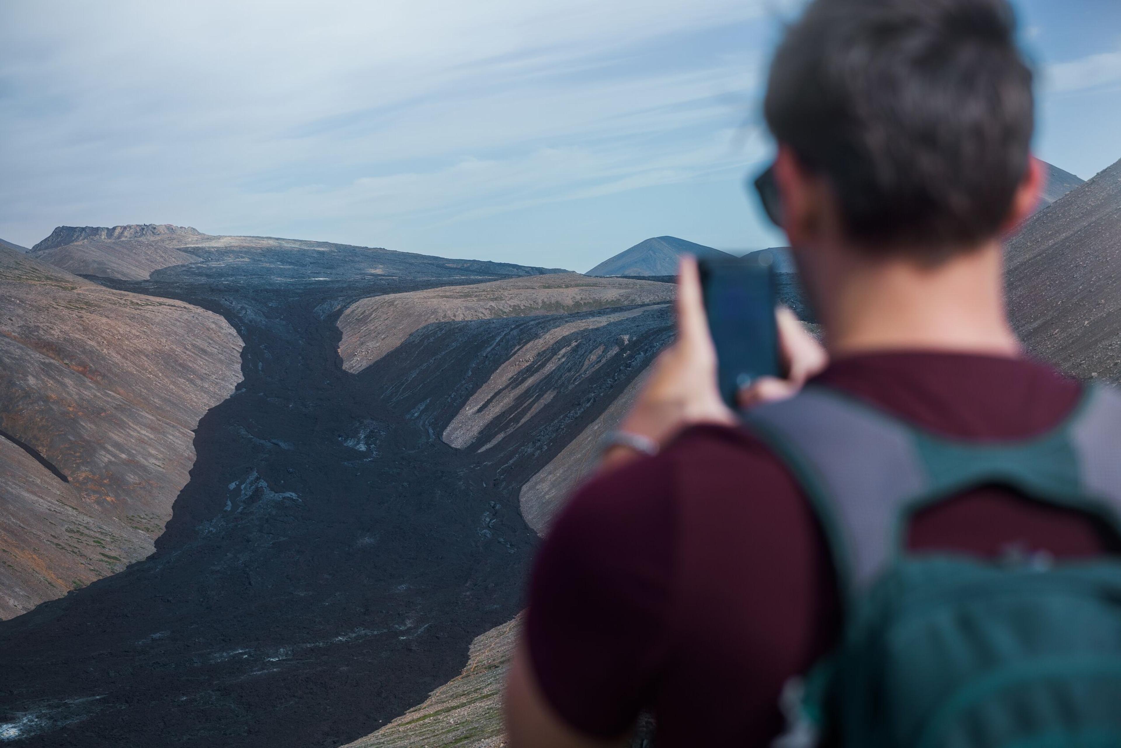 A person taking a picture of the lava field near the Fagradalsfjall area