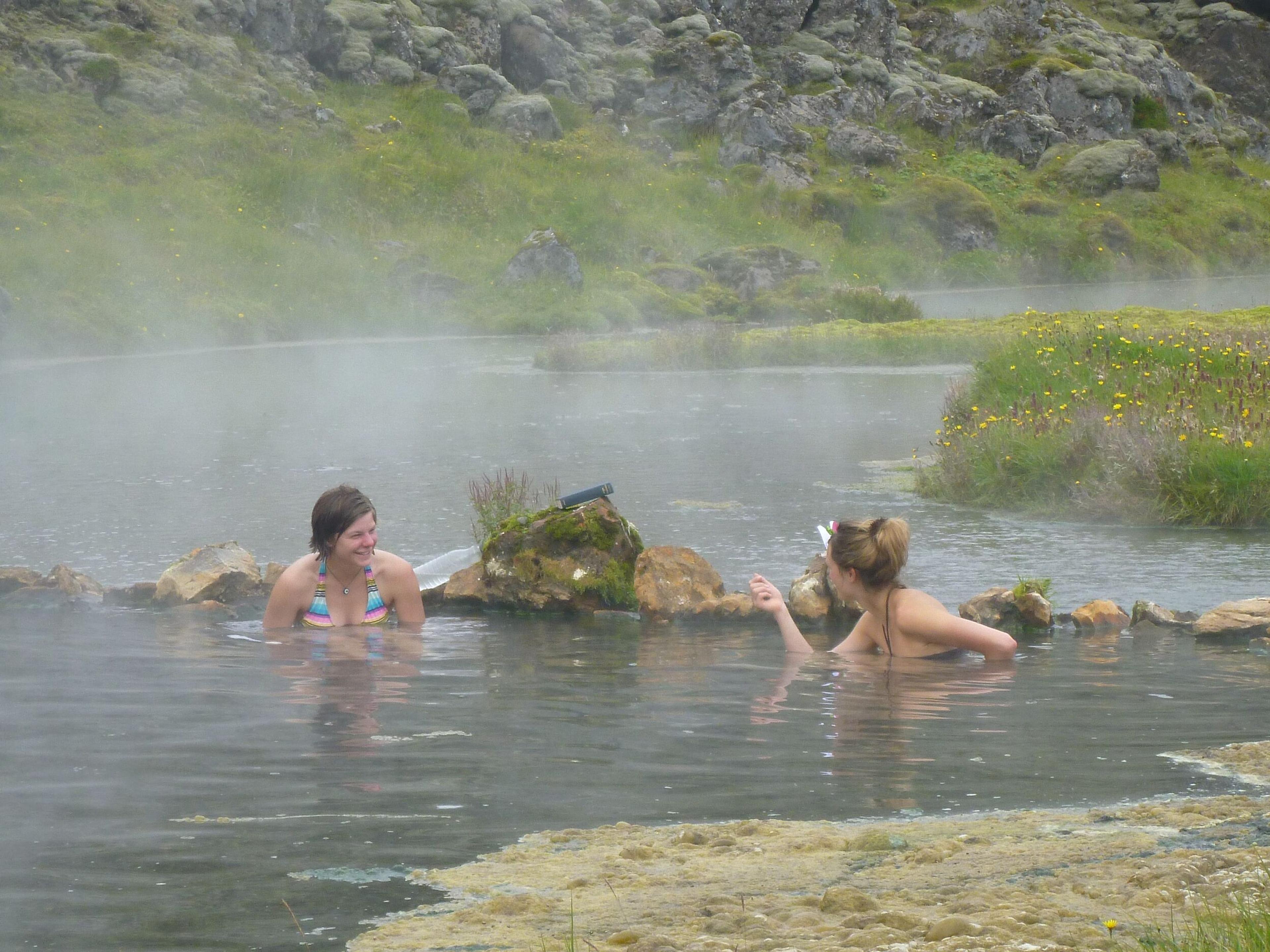 two women are swimming in a hot spring .
