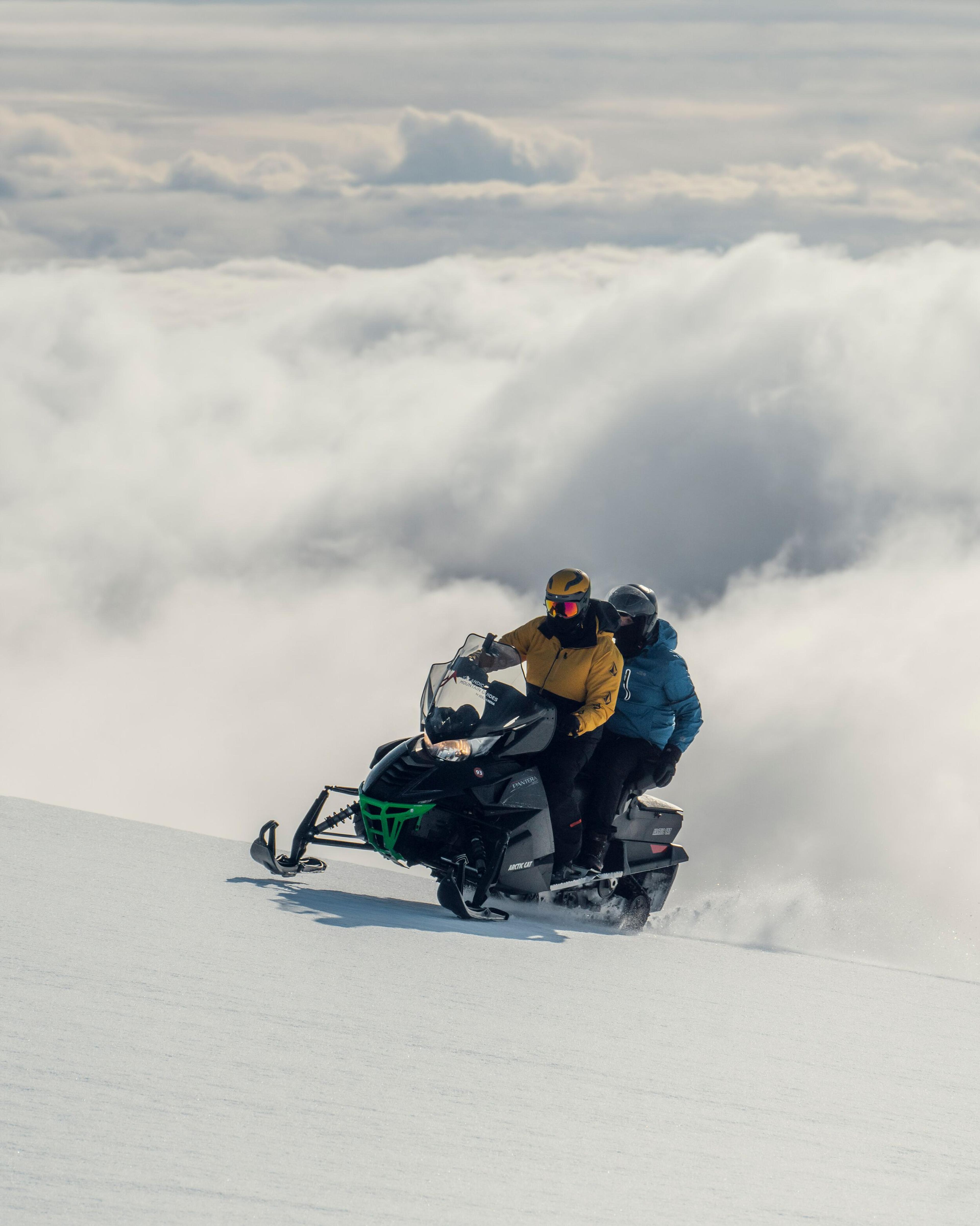 Two people riding a snowmobile on a glecier in Iceland.