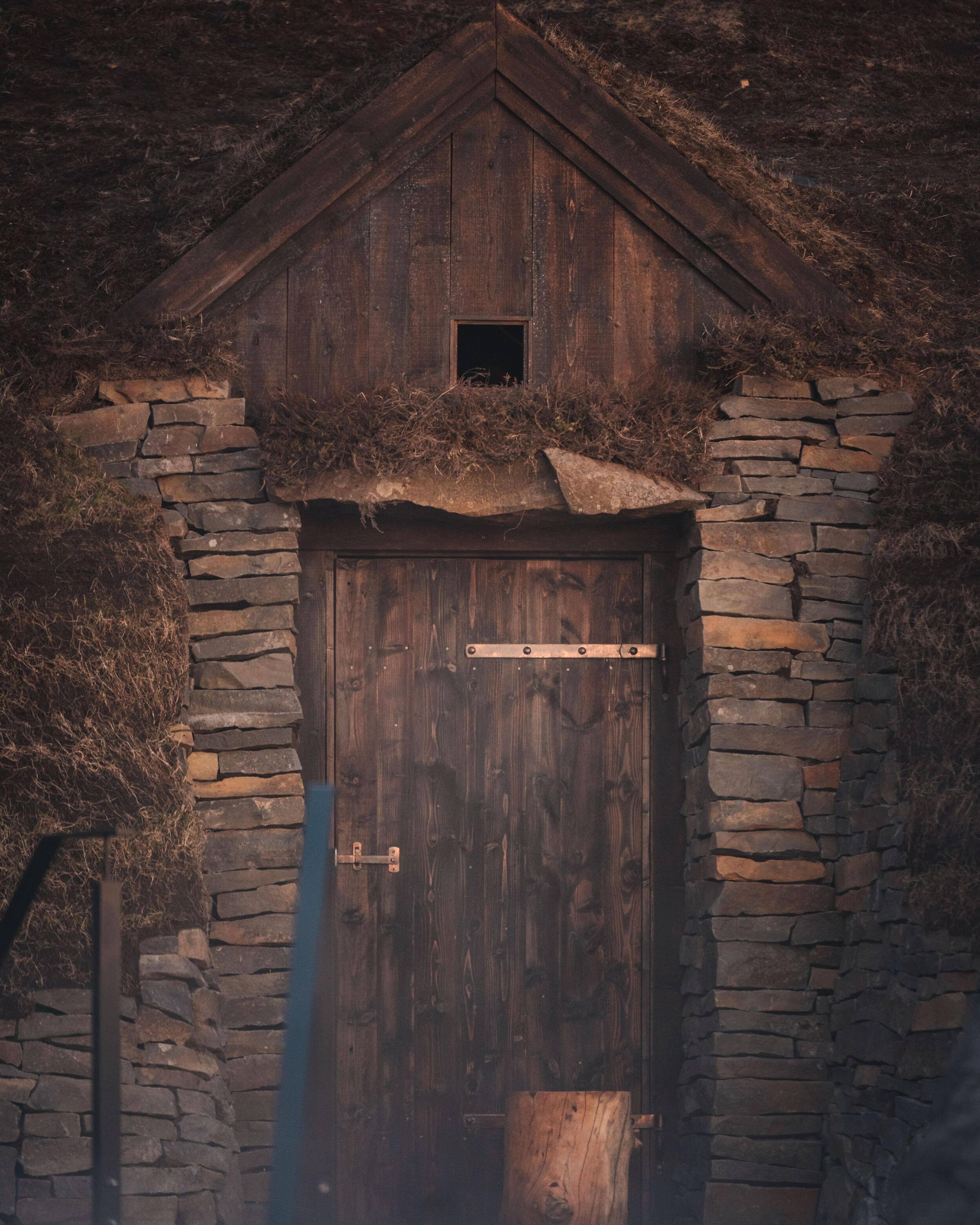 A traditional turf house door at Sky Lagoon Iceland, featuring rustic stone walls and a grass roof, invoking the historic architecture of the region.