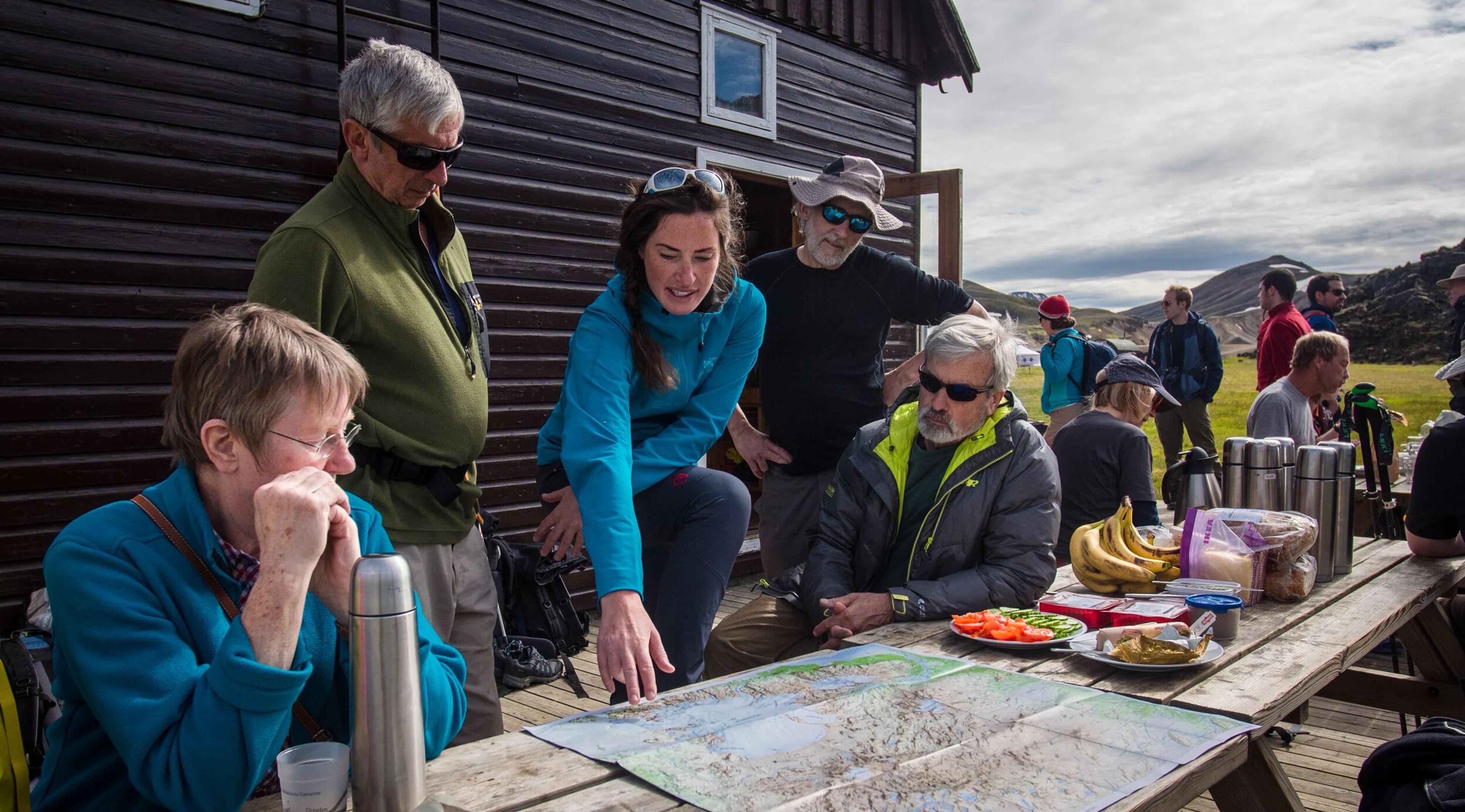 Group of hikers gathered around a table, reviewing maps and planning a hike in Landmannalaugar.