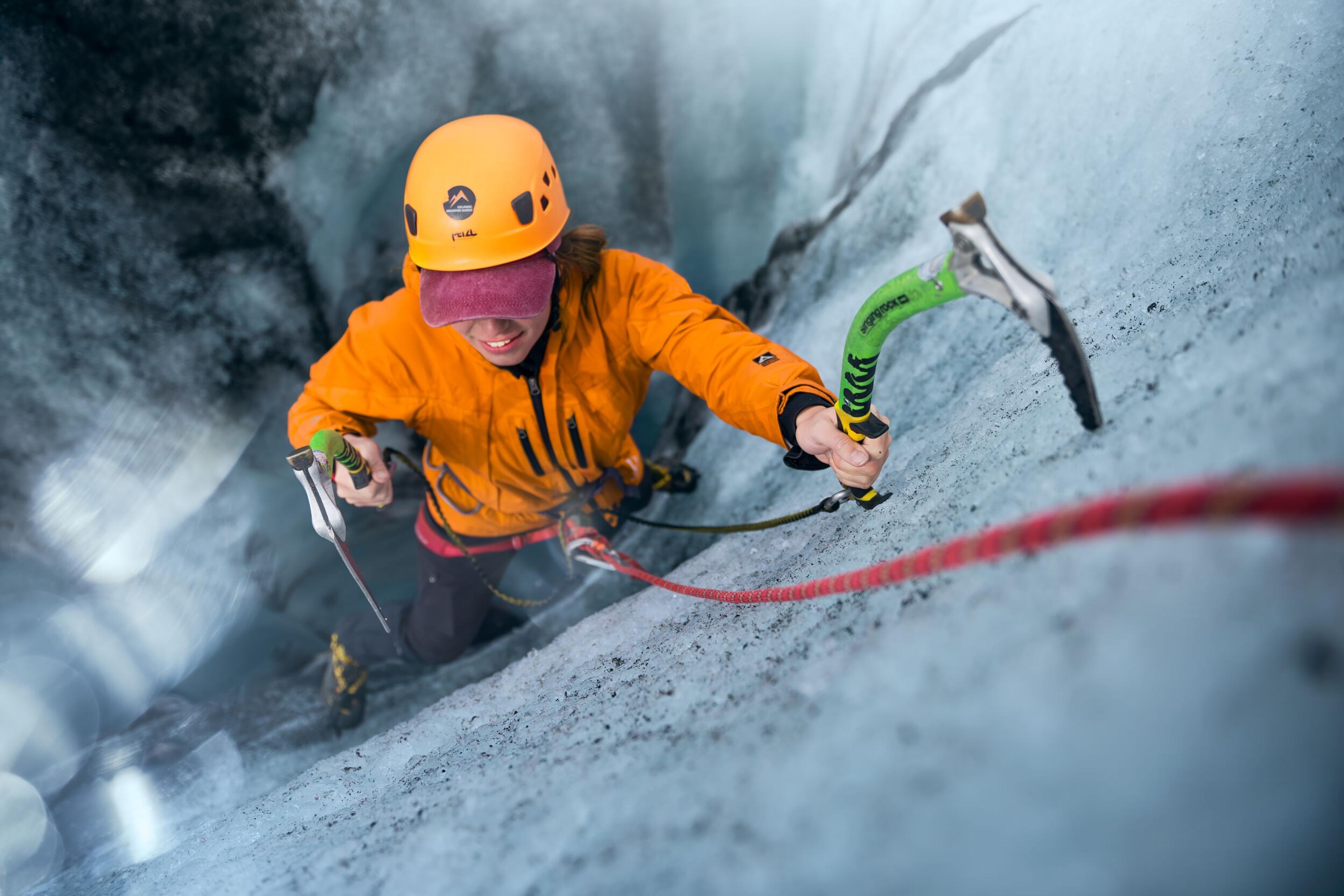 Hiker climbing a glacier wall on Sólheimajökull in the south coast of Iceland