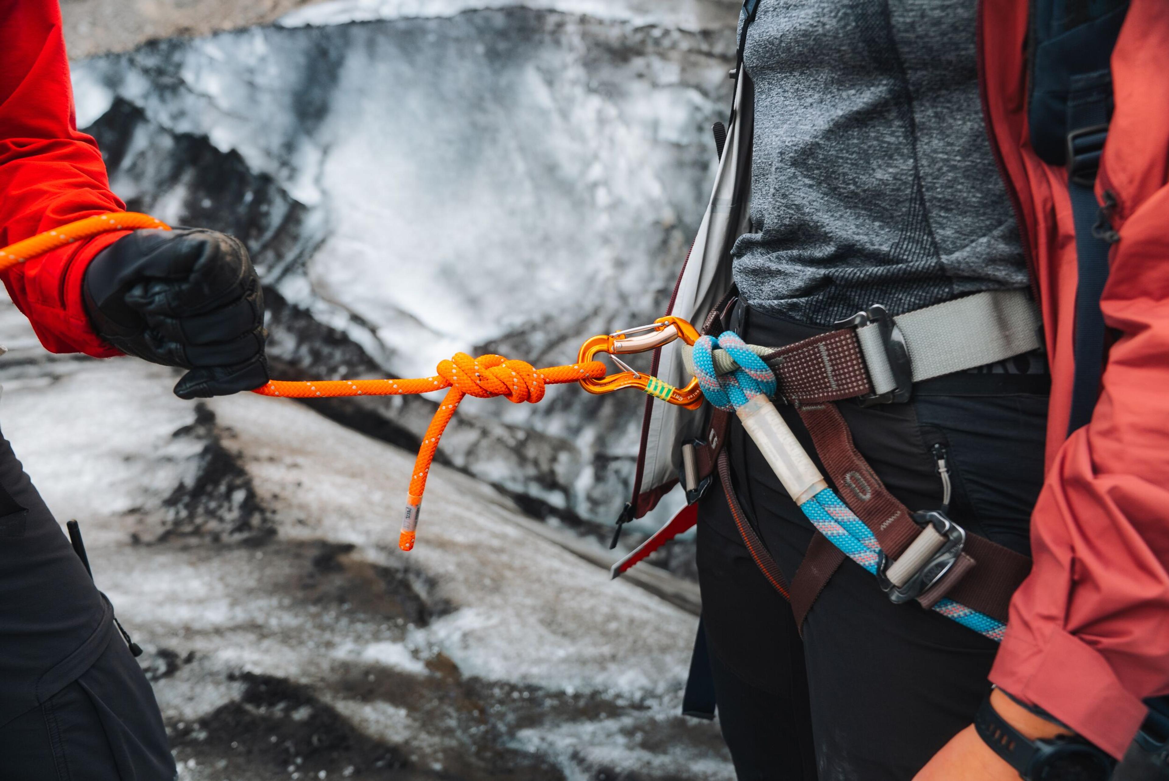 a person is tying a rope to a carabiner on a rock .
