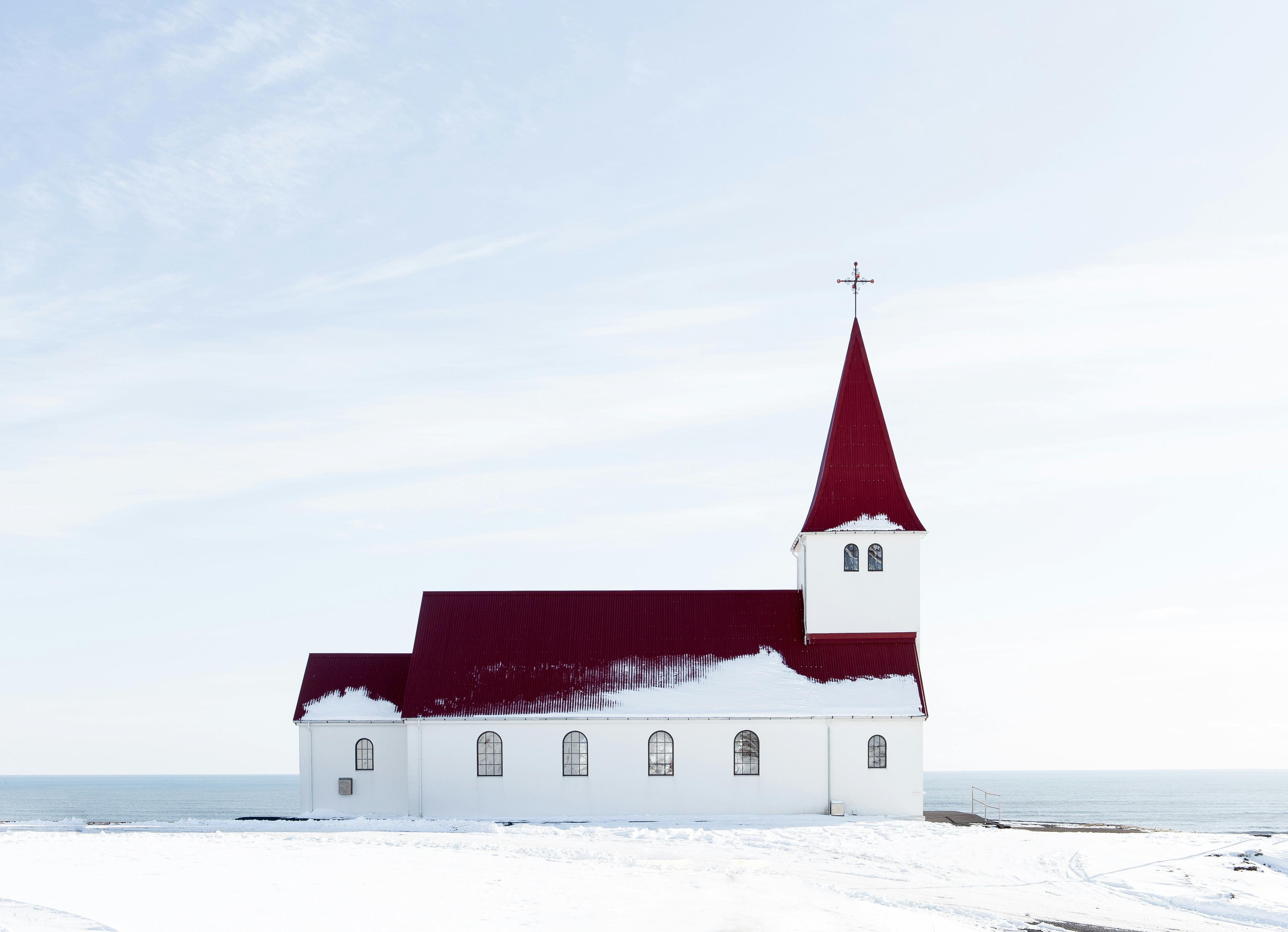 Close-up of Vík's red-roofed church covered in snow, set against a serene winter backdrop.