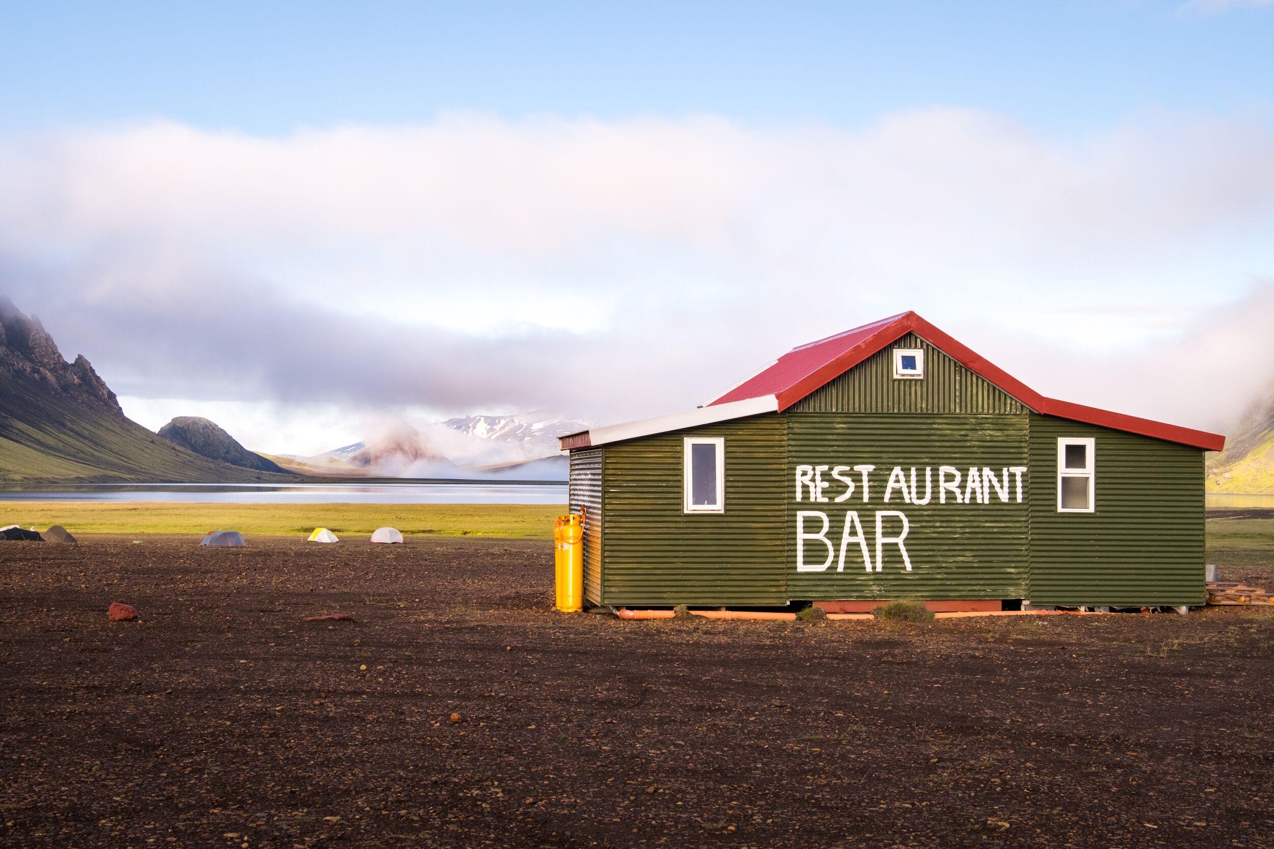 Álftavatn Hut, Set in Stunning Mountain Scenery, a Green House with Restaurant Bar Sign stands out.
