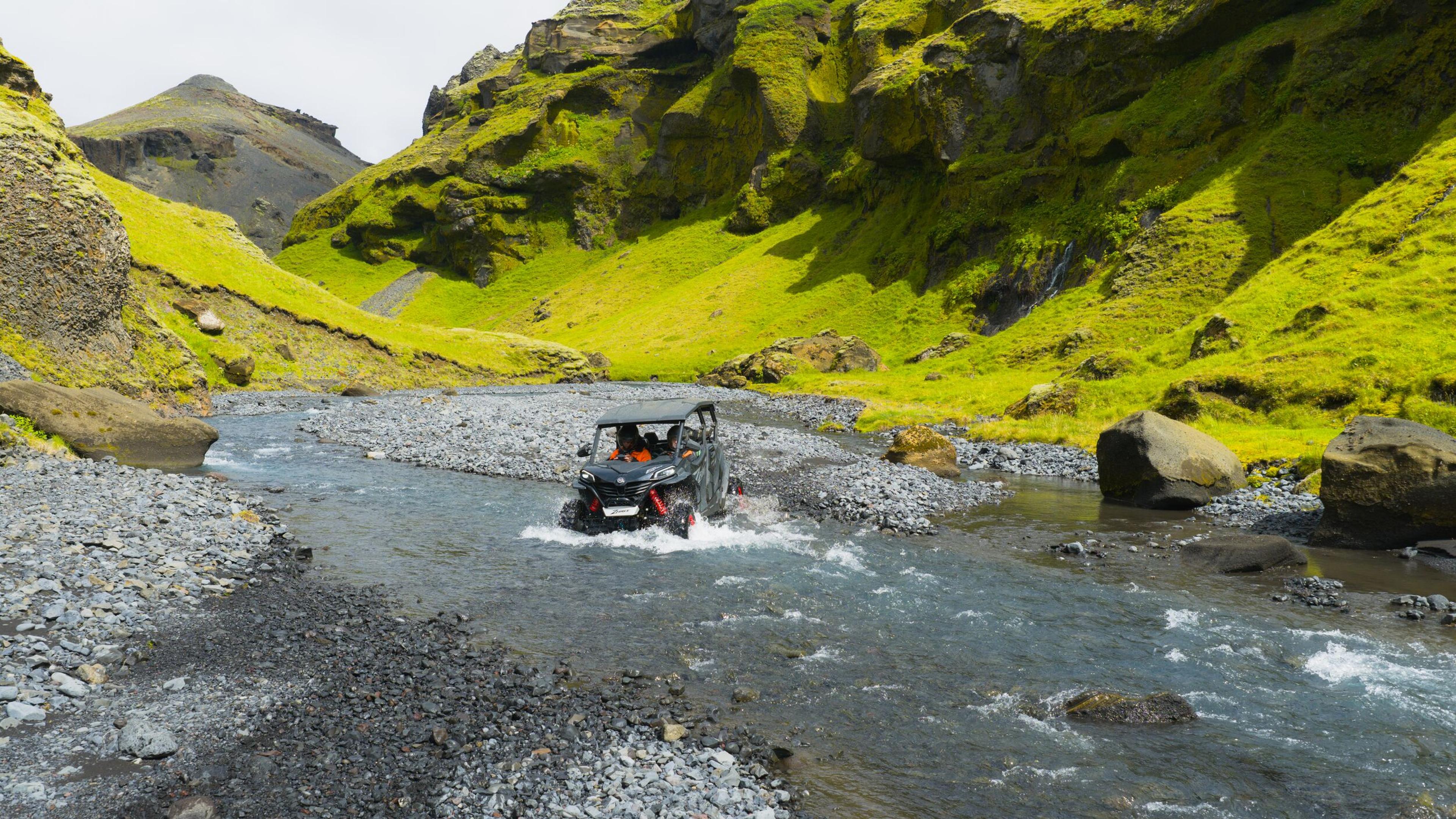 a person is driving a atv through a river .