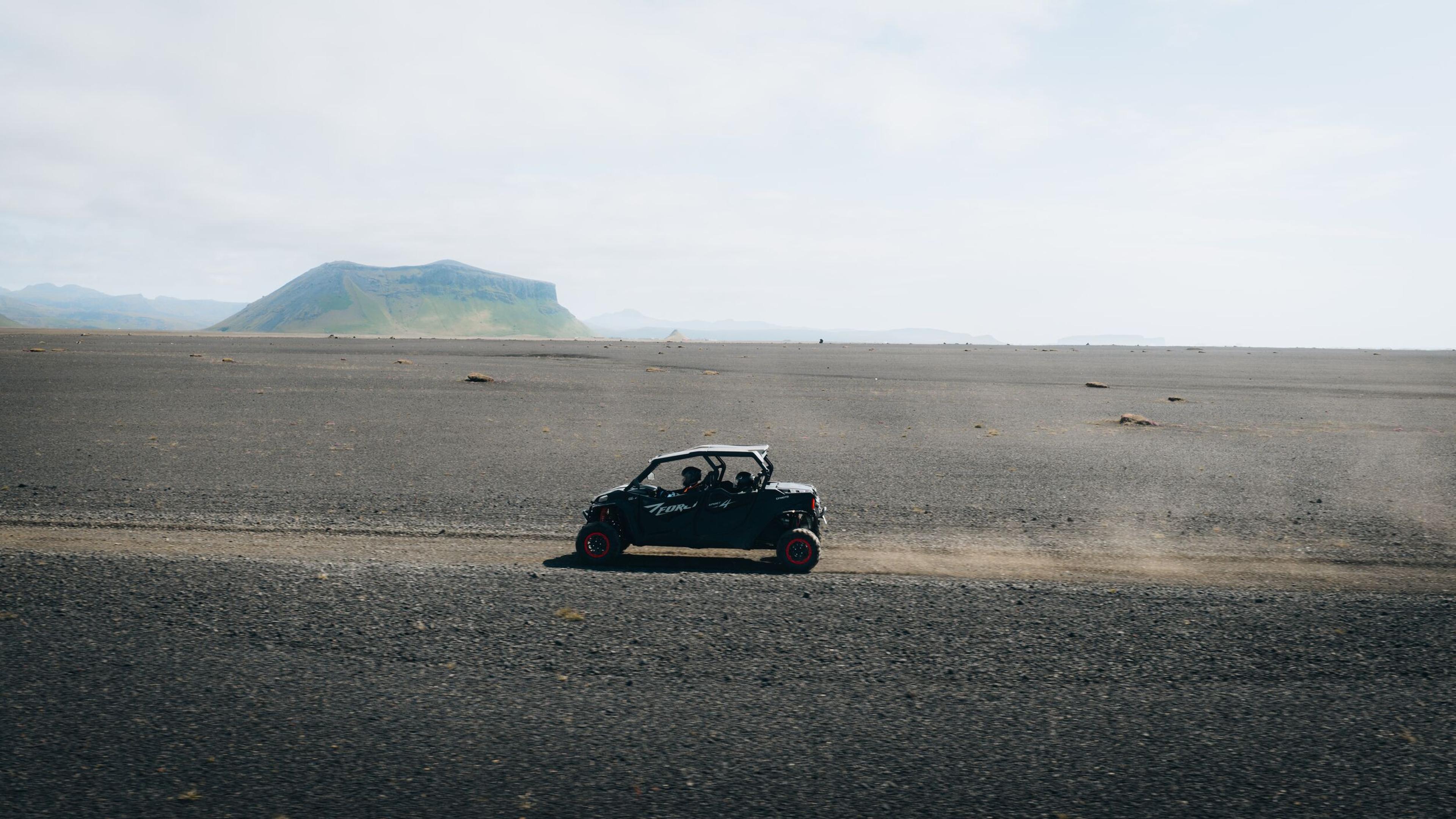 a person is driving a buggy on a dirt road in the desert .