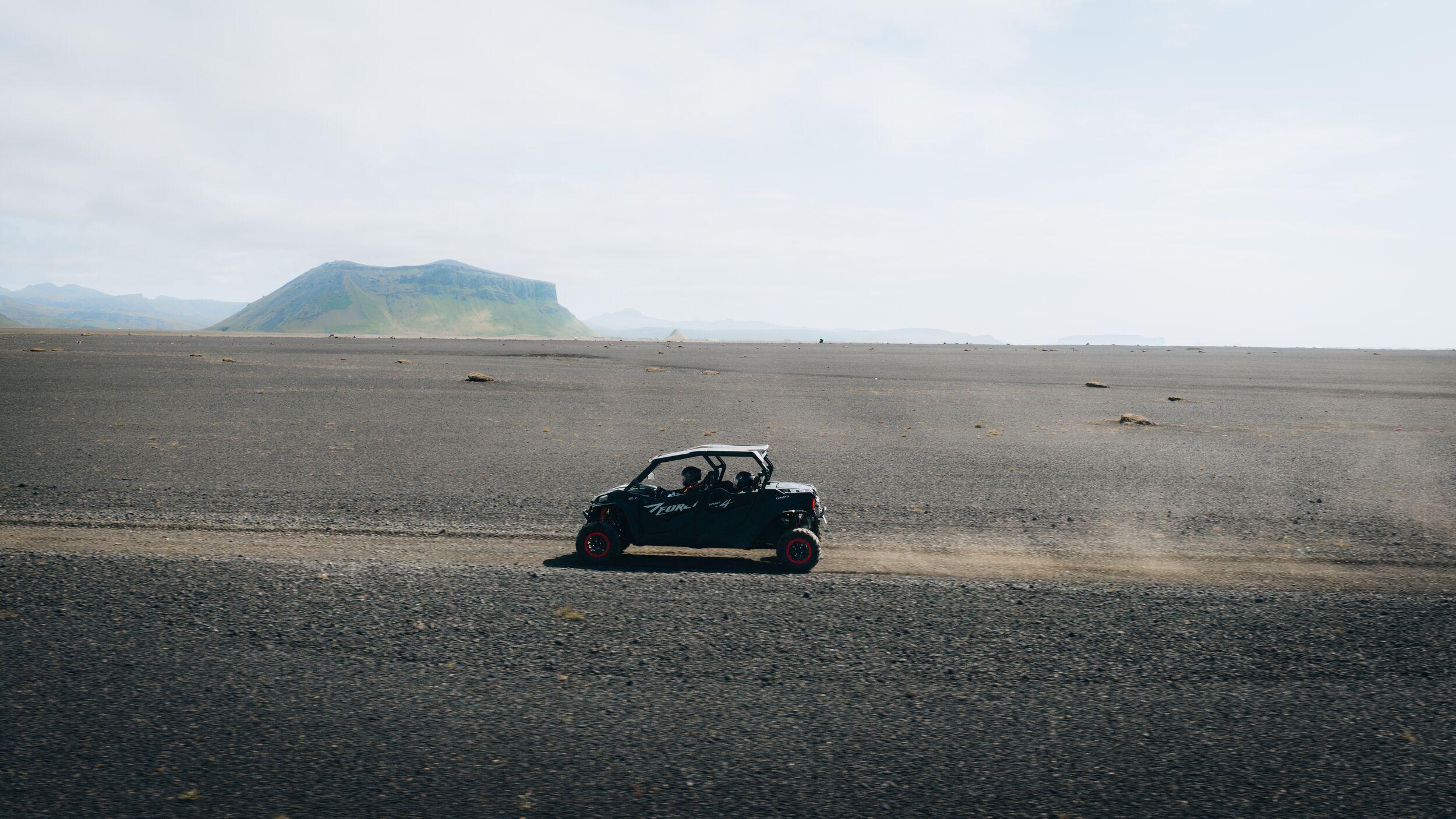 a person is driving a buggy on a dirt road in the desert .