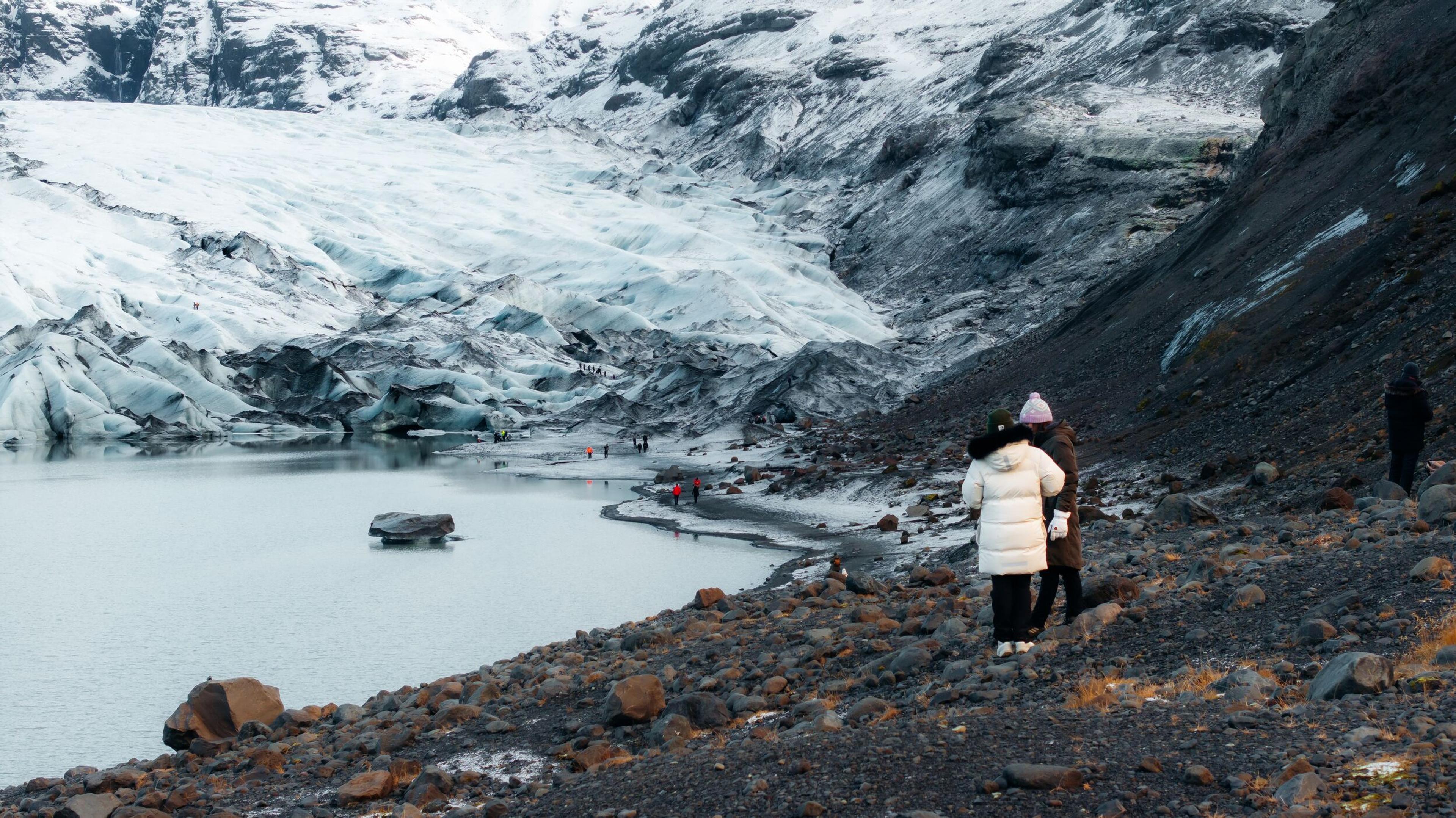 Tourists observe a large glacier and glacial lake from the view point