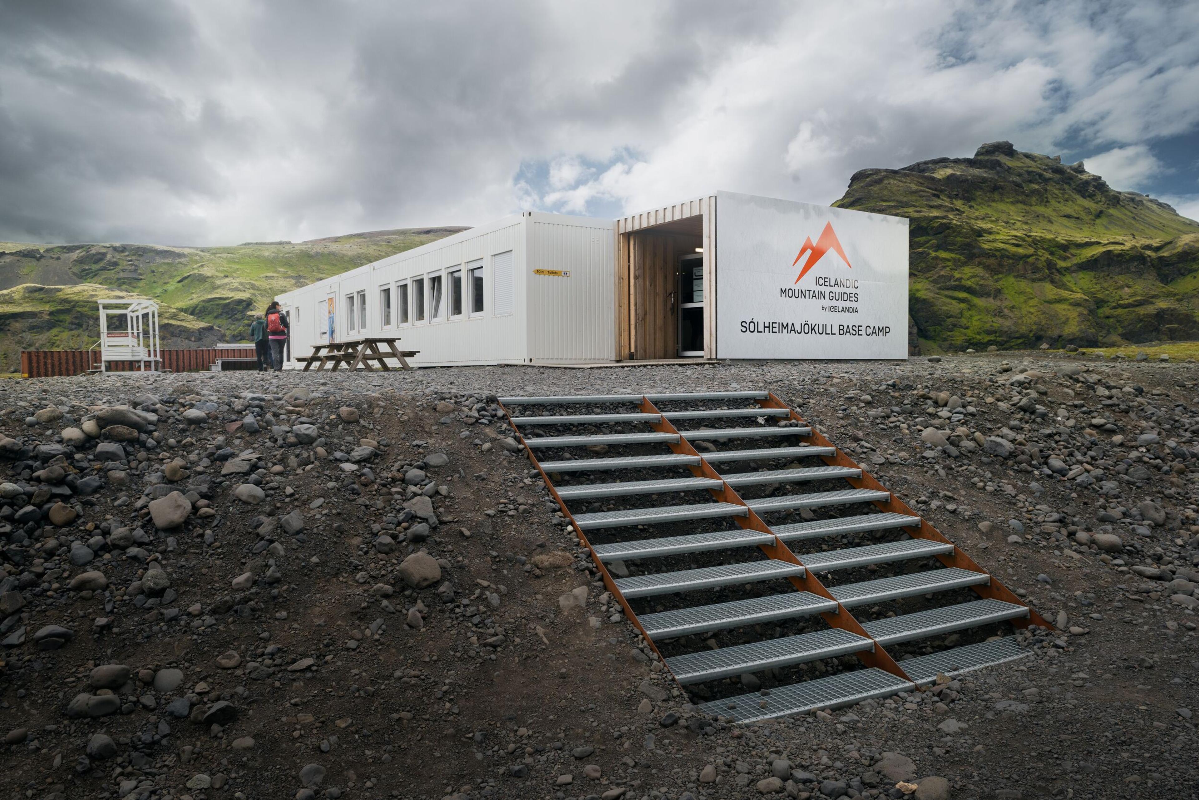 Sólheimajökull Basecamp: Rocky Terrain, Backdrop of Mountains, and Distinctive White Base