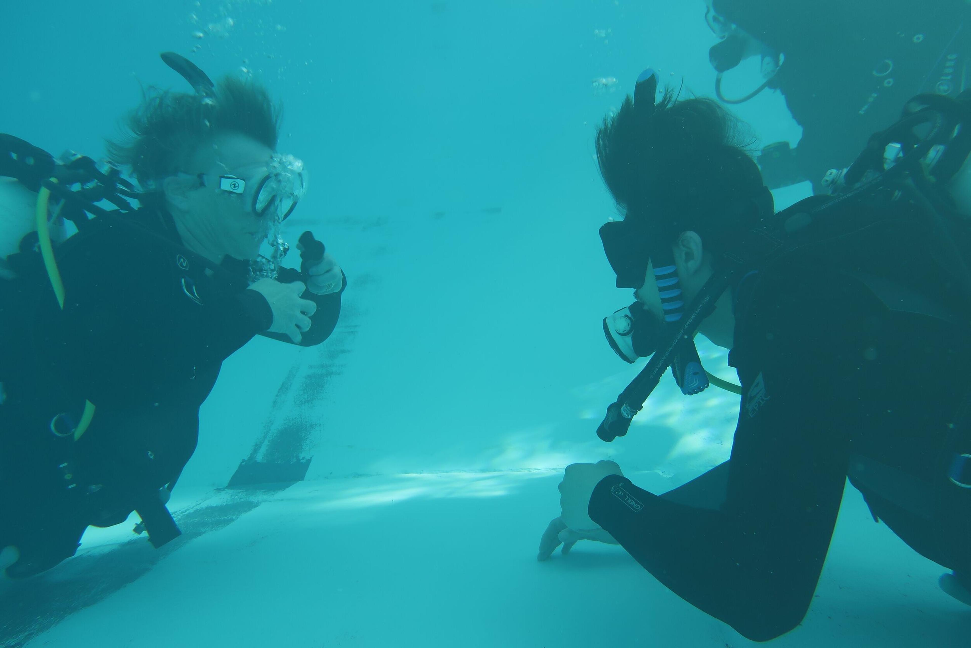Two scuba divers underwater, one giving a thumbs-up.