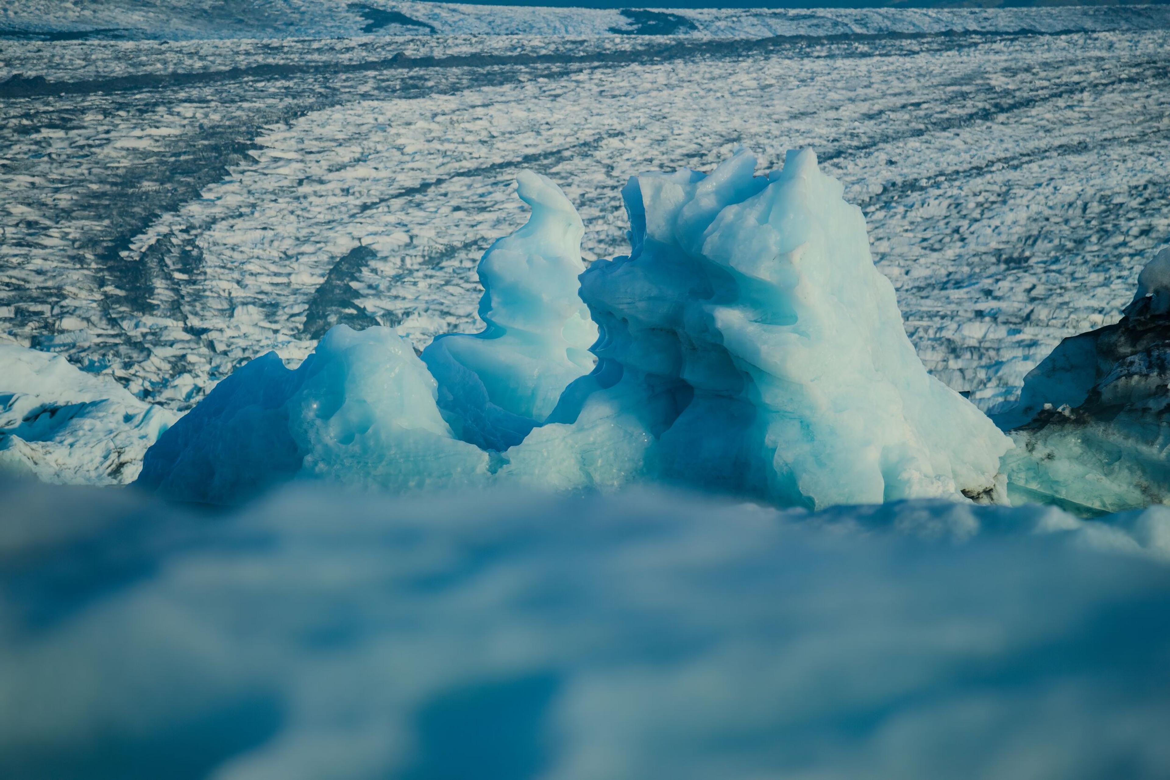 Close-up of blue ice formations with a textured icy landscape in the background.