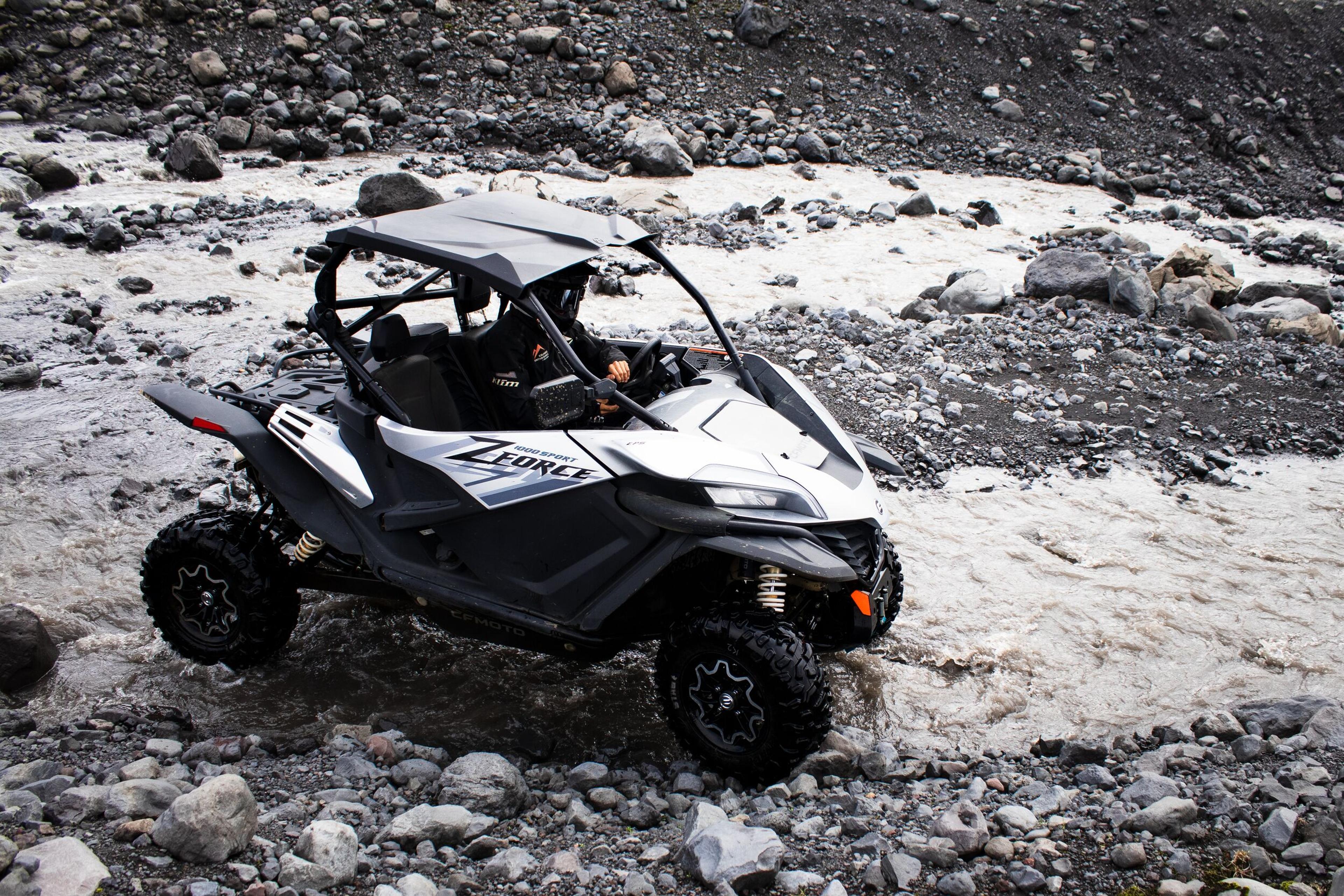 White off-road buggy navigating rocky riverbed on the South Coast of Iceland.