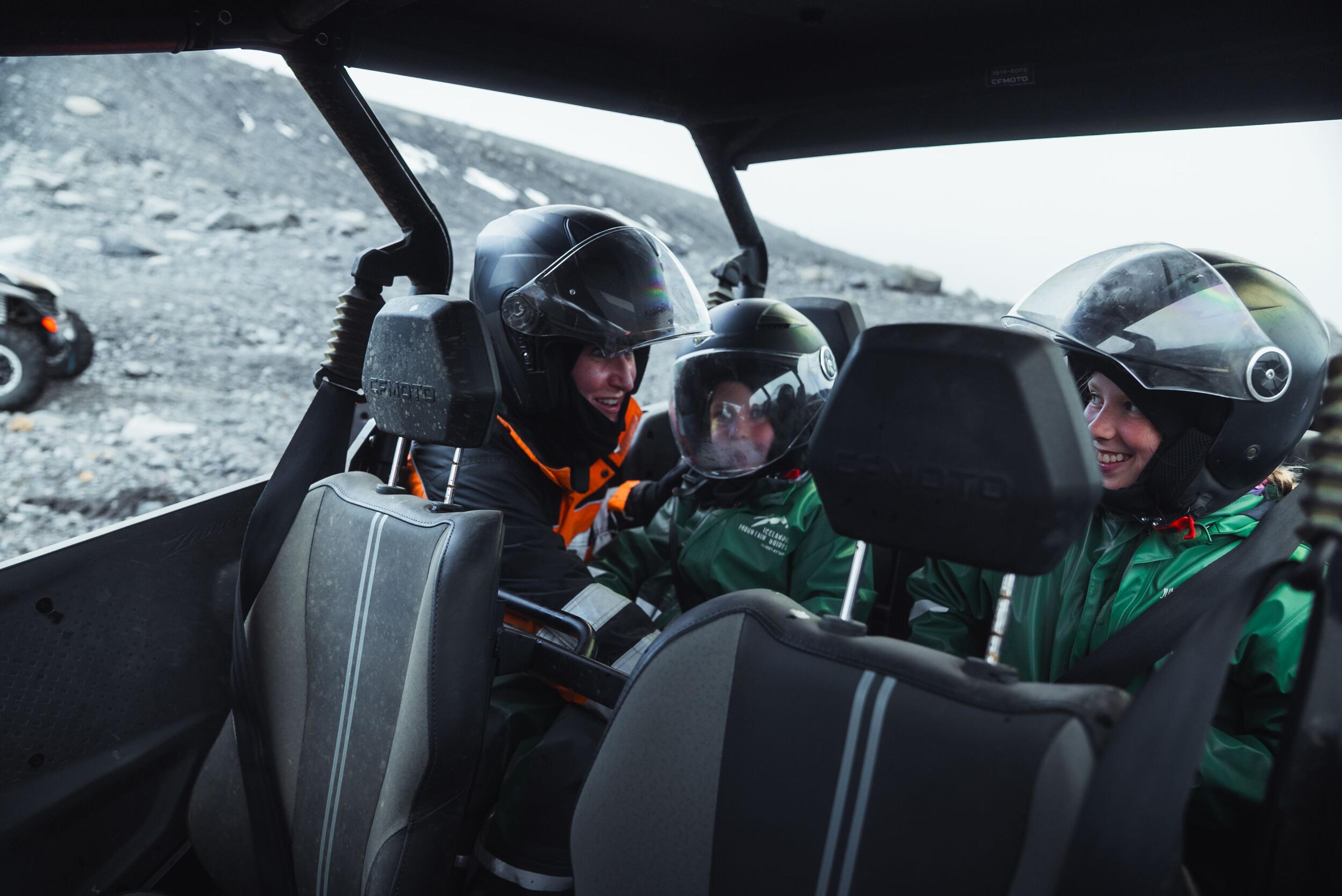 a group of people wearing helmets are sitting in the back seat of a vehicle .