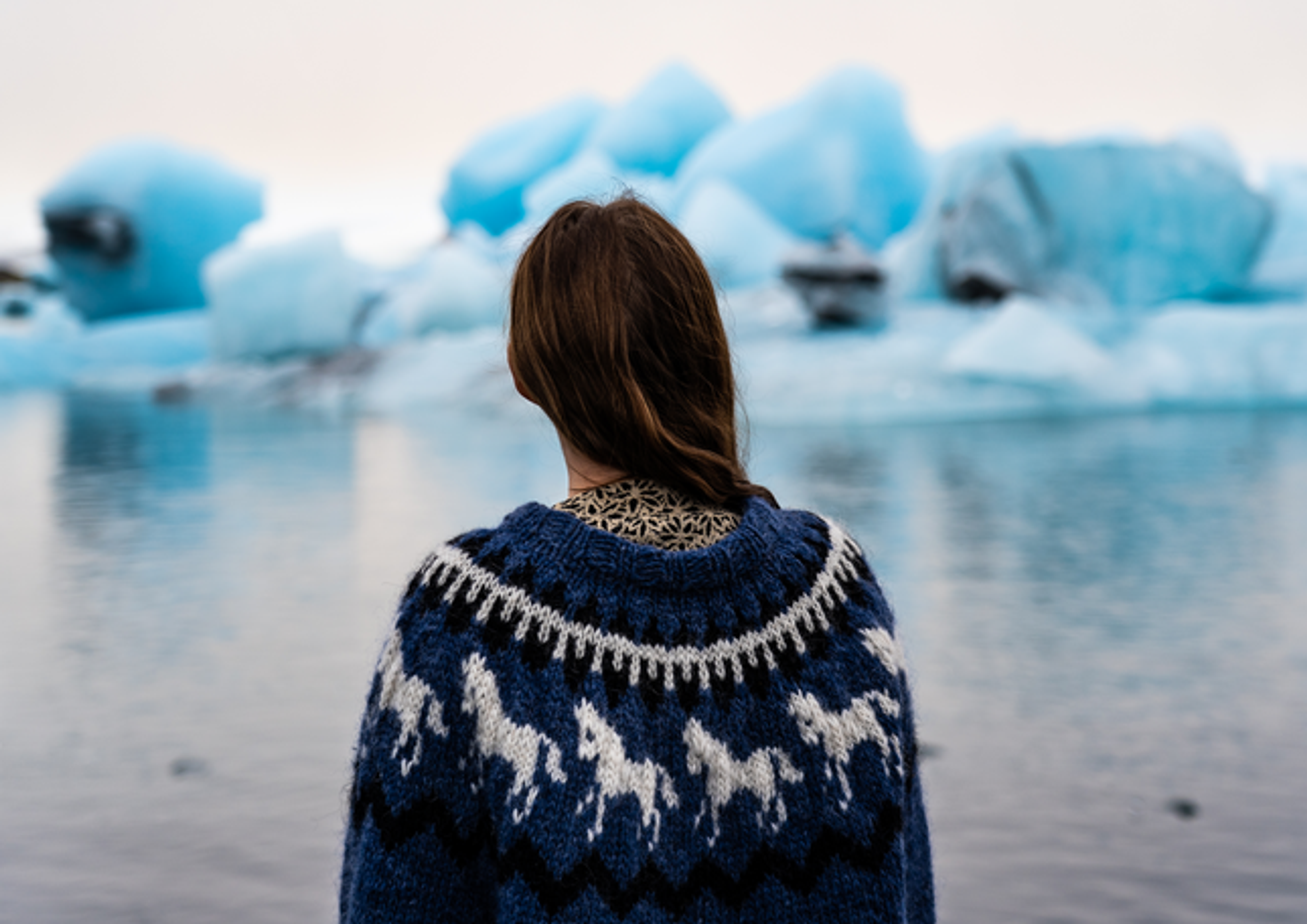 A woman looking at the calm icebergs floating on the glacial lagoon
